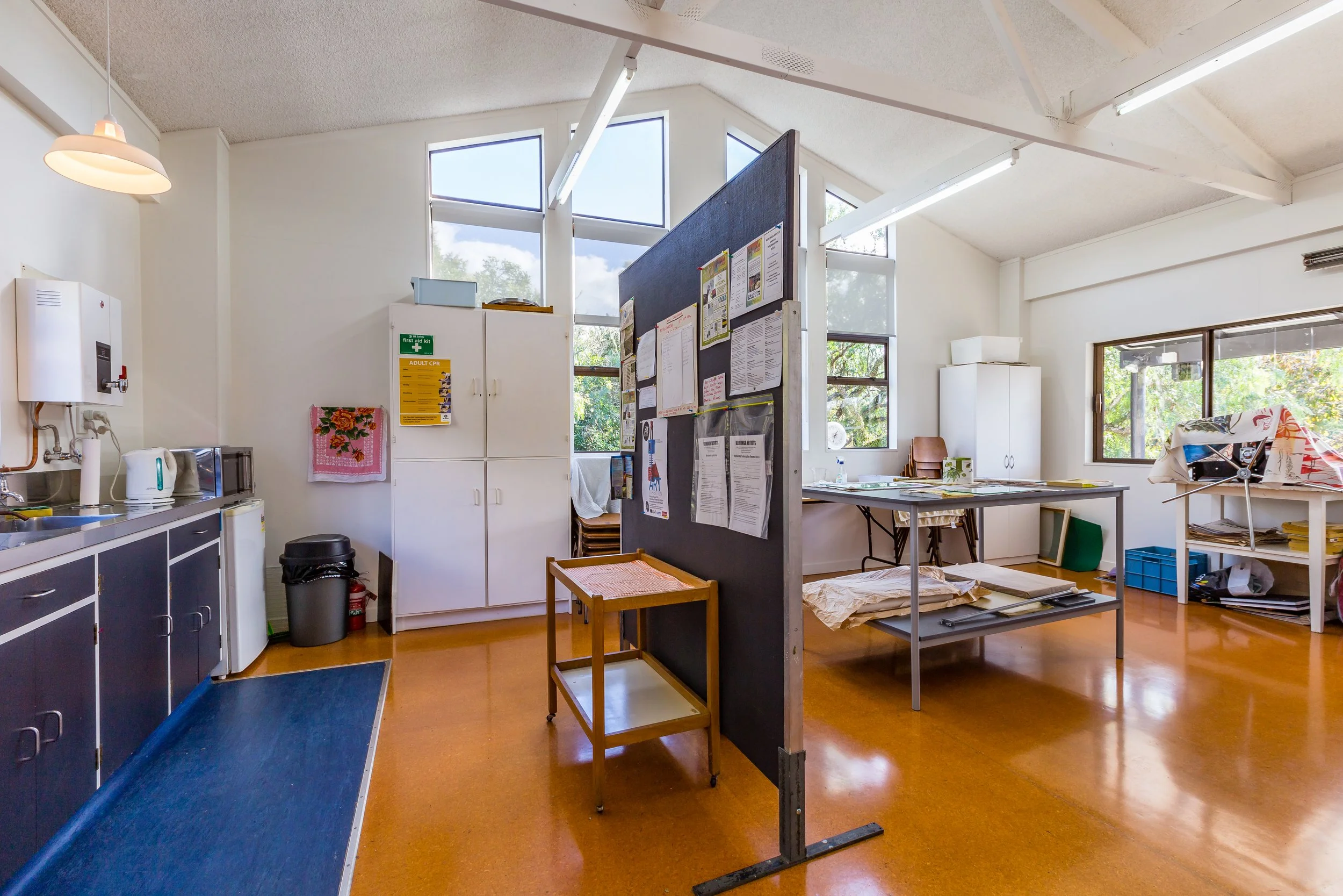 Interior of a kitchen and break room with cabinets, tables, and windows.