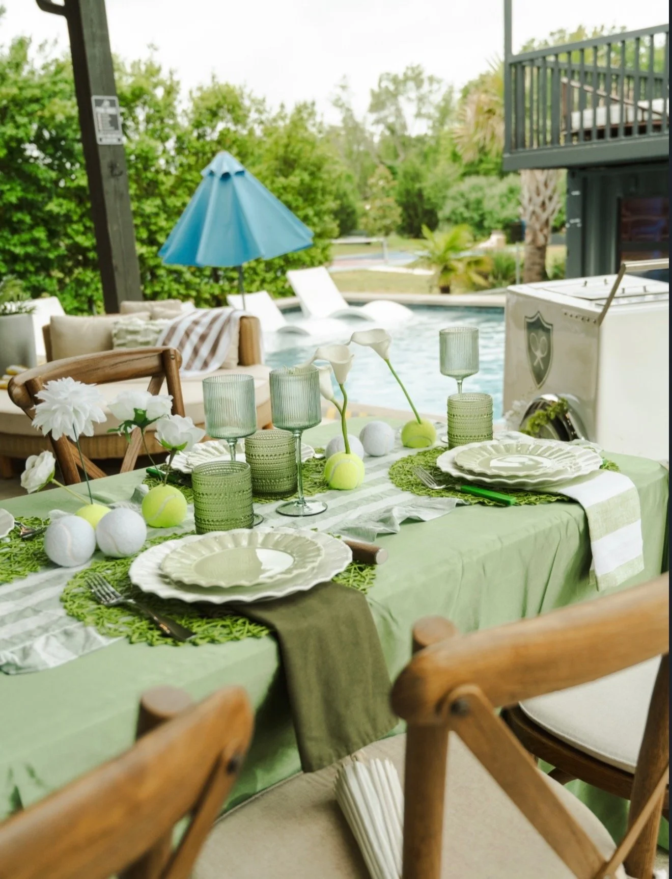 Outdoor pool party tablescape featuring green linens, tennis ball decor, white flowers, and glassware styled for a social celebration by Ignited Events in Dallas Fort Worth, Texas