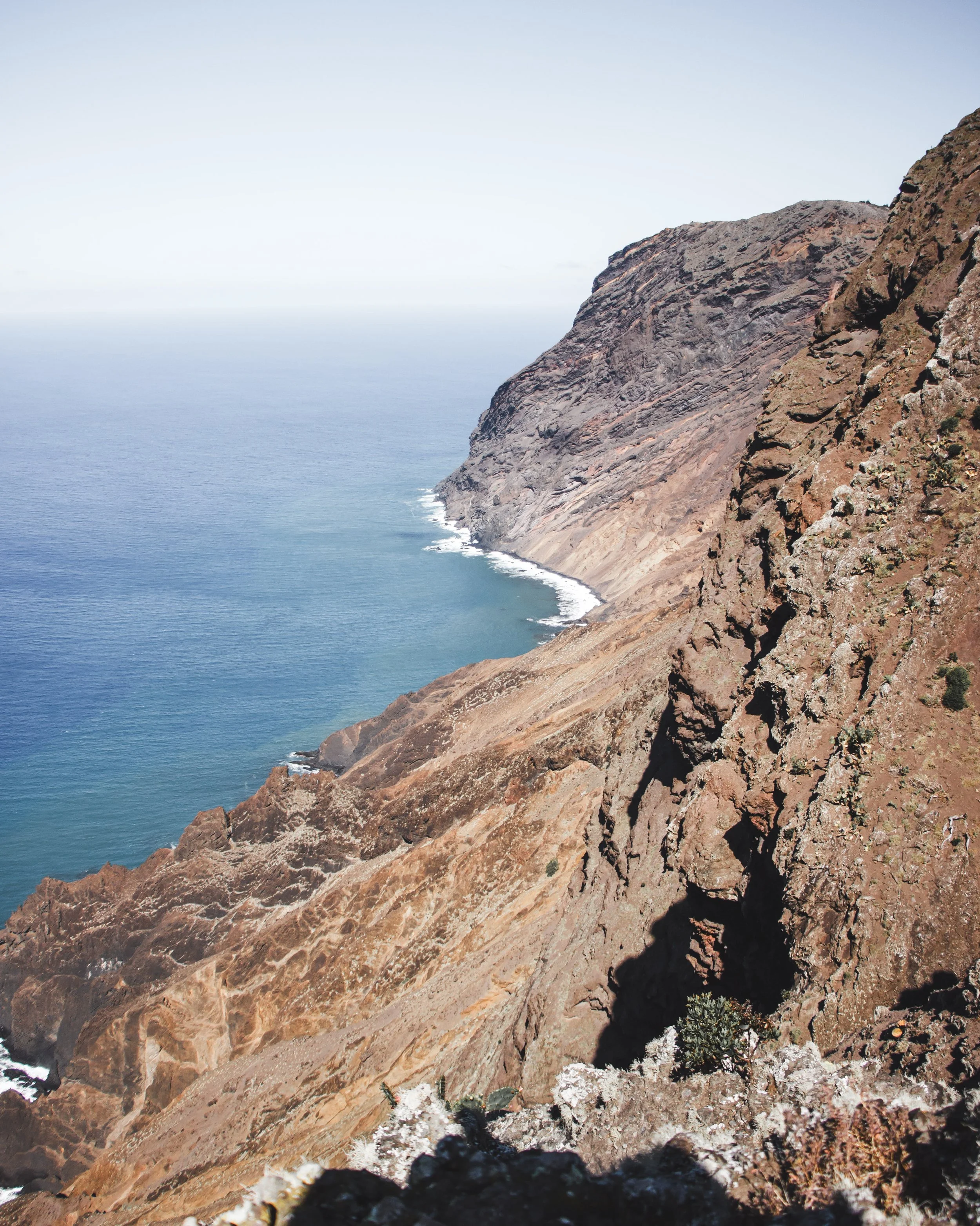 Cliffs overlooking the ocean with clear blue water and rocky formations.