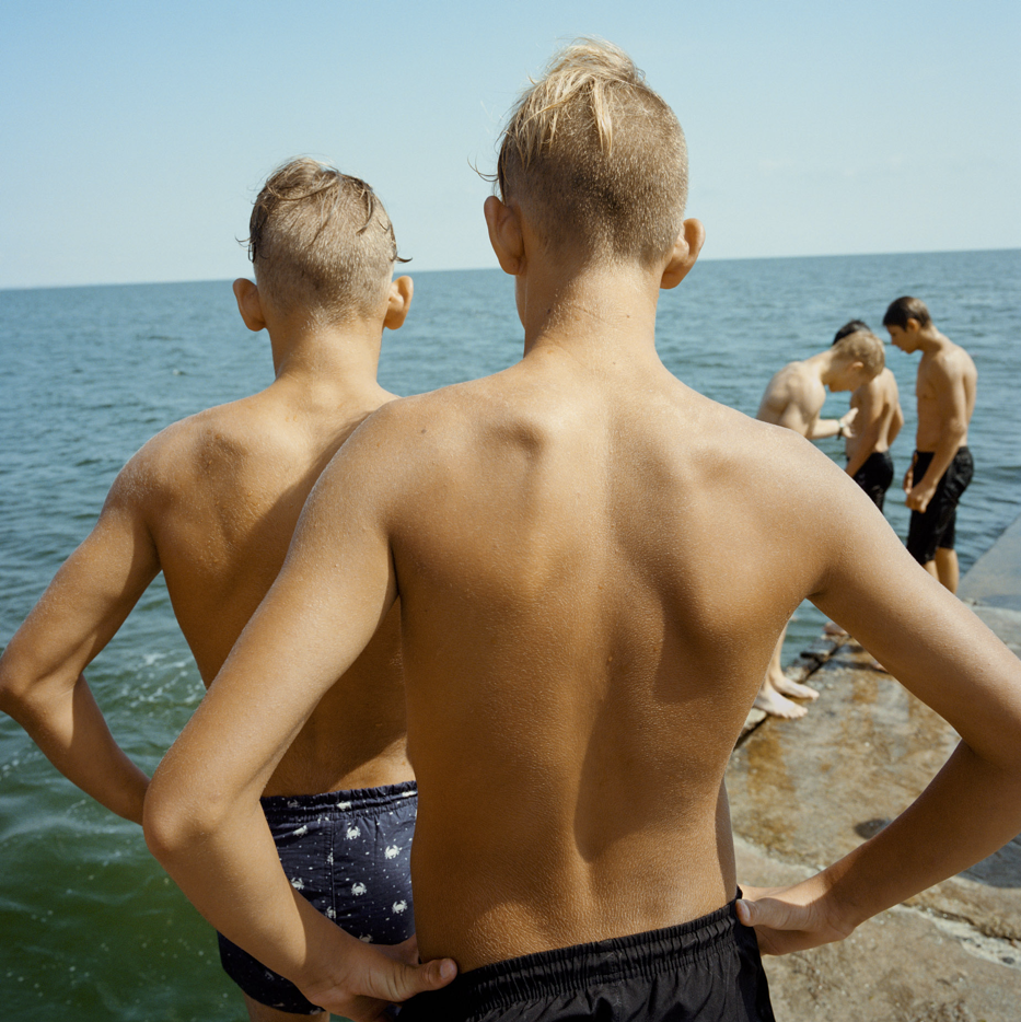    Patrick Wack. Azov Horizons. 2029.ongoing.        "Summer 2023. Ukraine. Young Ukrainians jump into the Black Sea from a pier in Odessa..".  