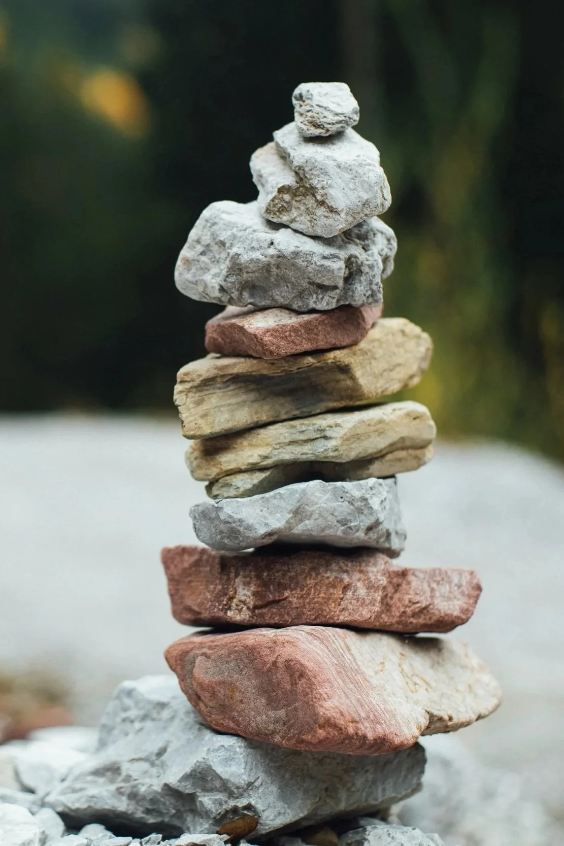 Stacked rocks of various sizes and colors balanced on top of each other outdoors.