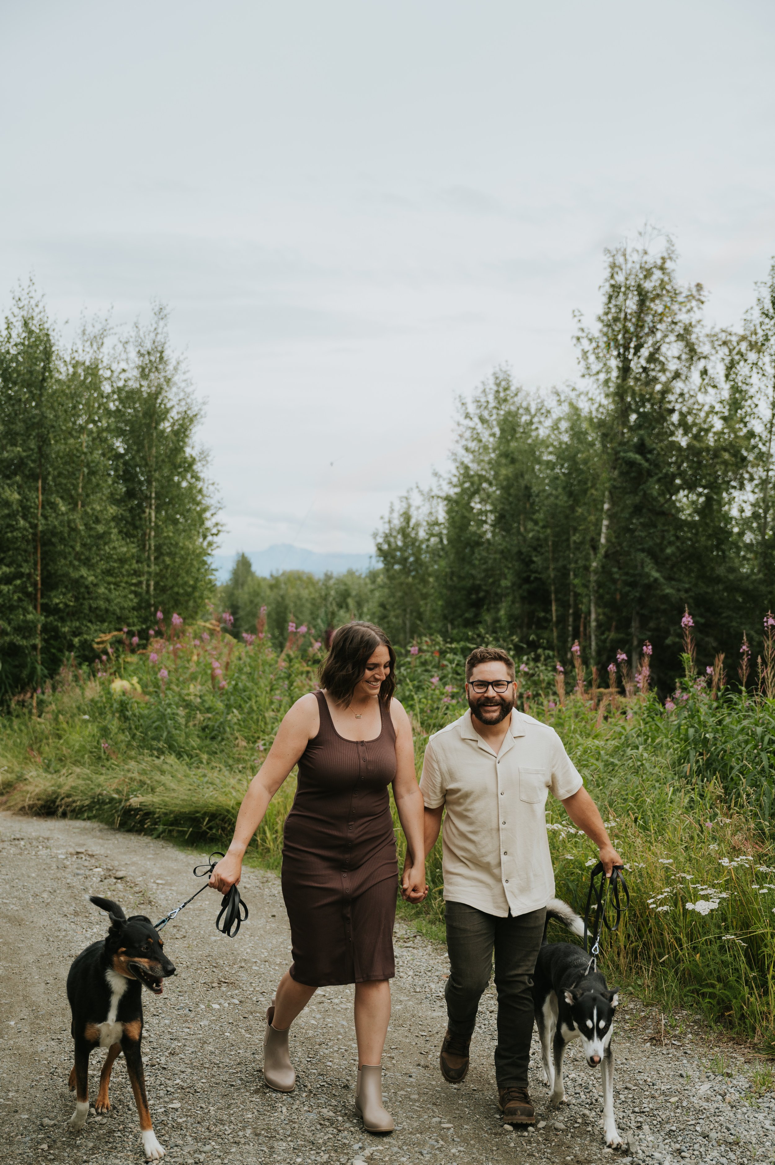 couple walking up path with two dogs on leashes smiling