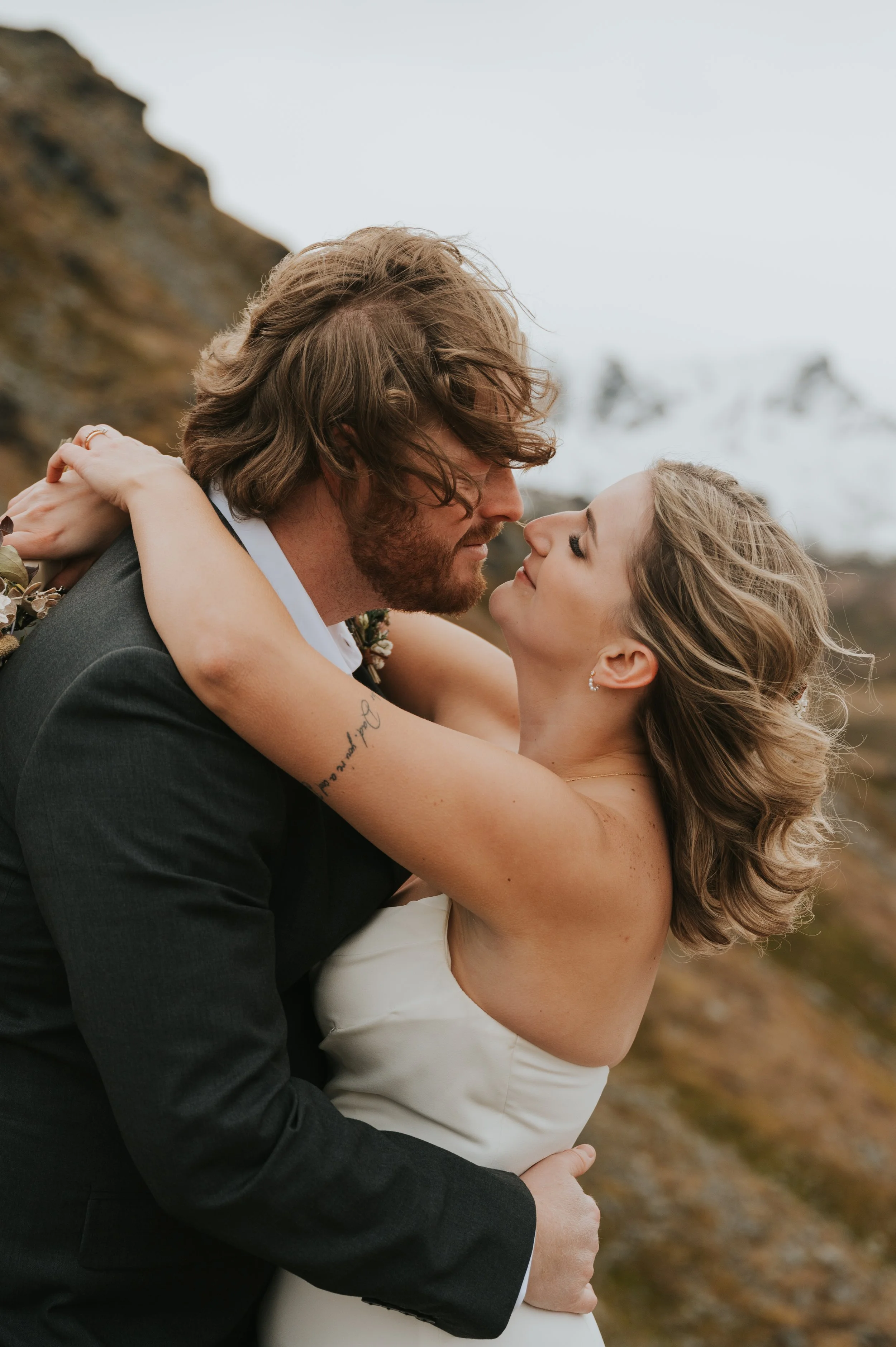 bride and groom touching noses with windswept hair