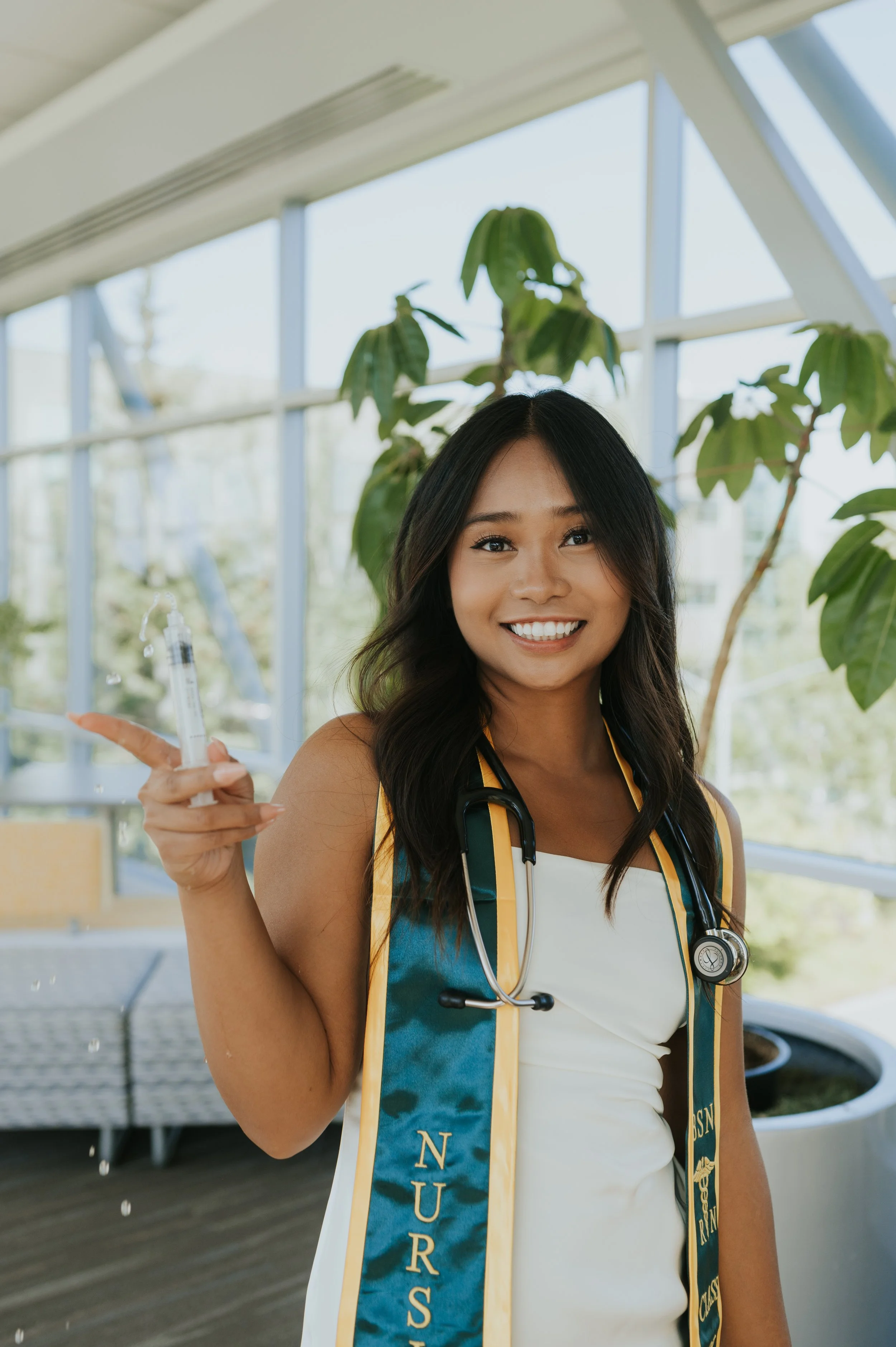 girl in graduation regalia pushing fluid from a syringe