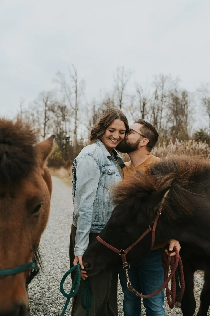 couple cuddling surrounded by their horses