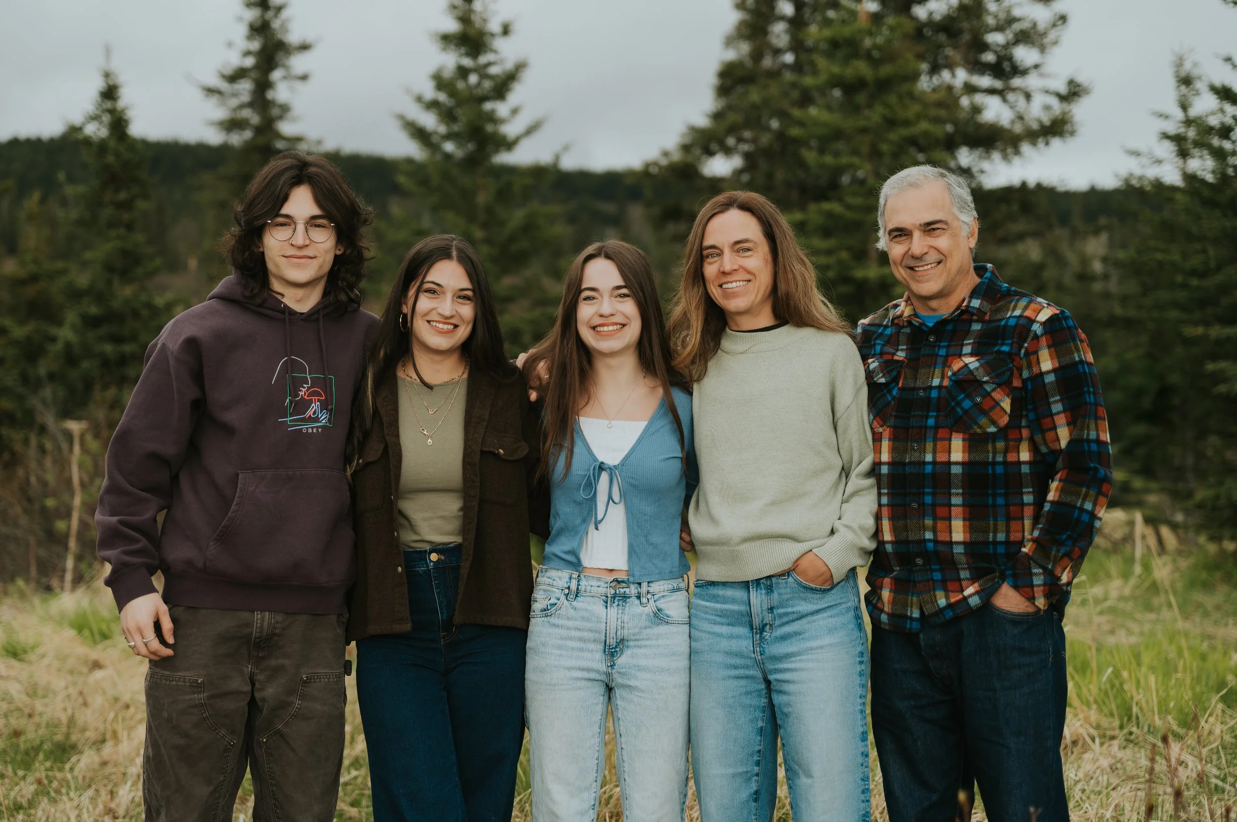 family with older siblings smiling at camera outside
