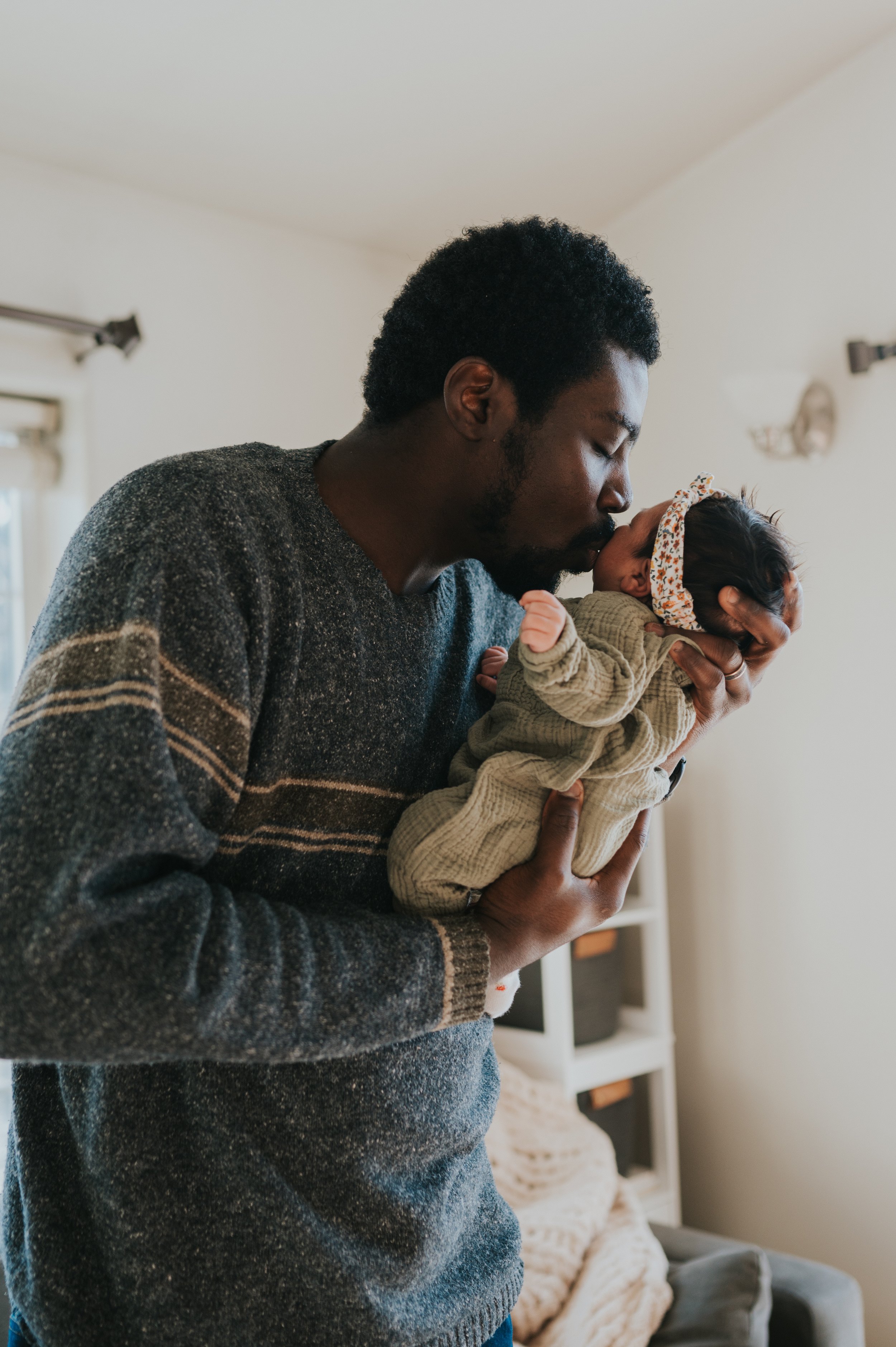 dad holding newborn baby giving kiss
