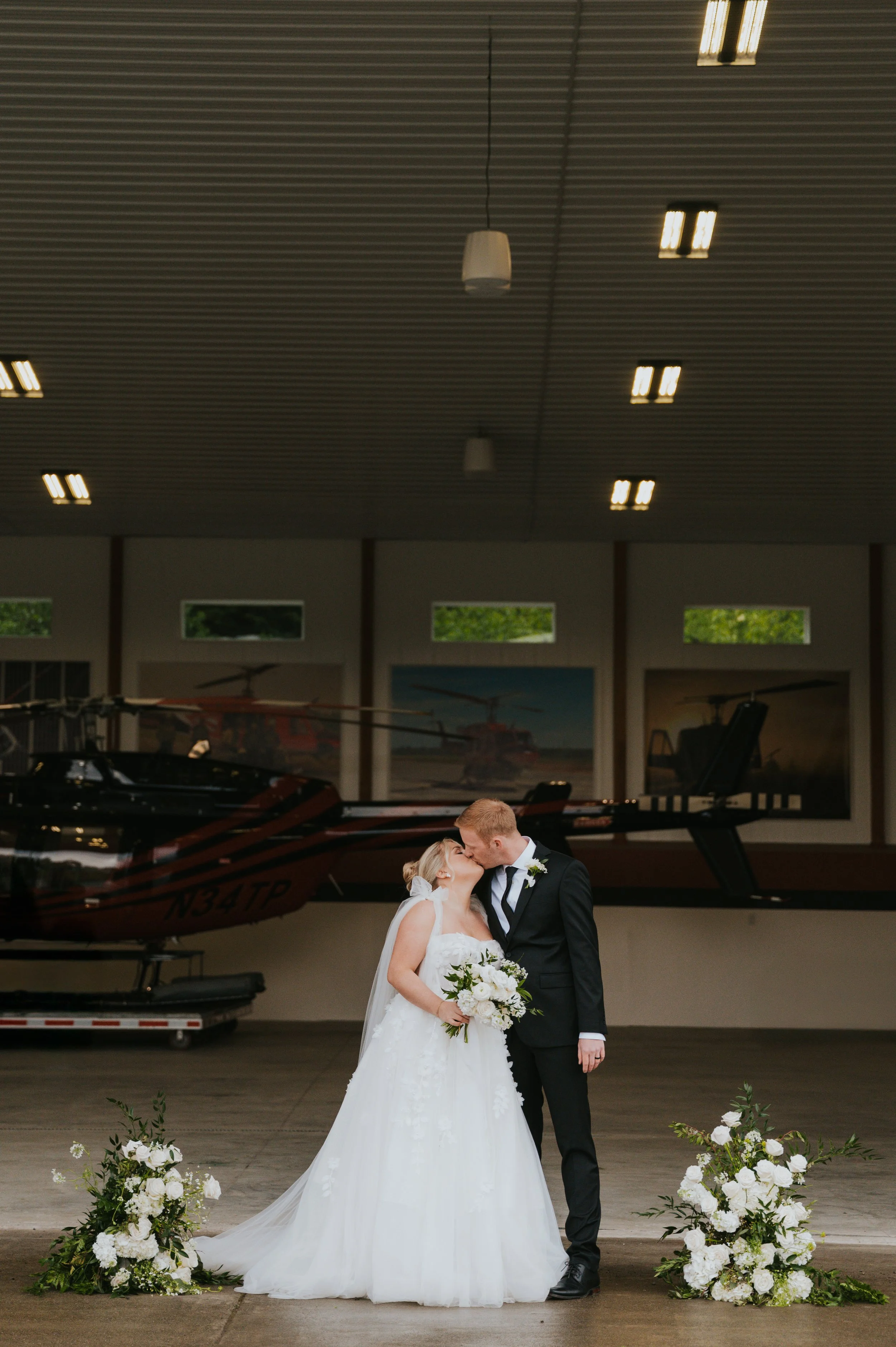 bride and groom kissing in airplane hangar
