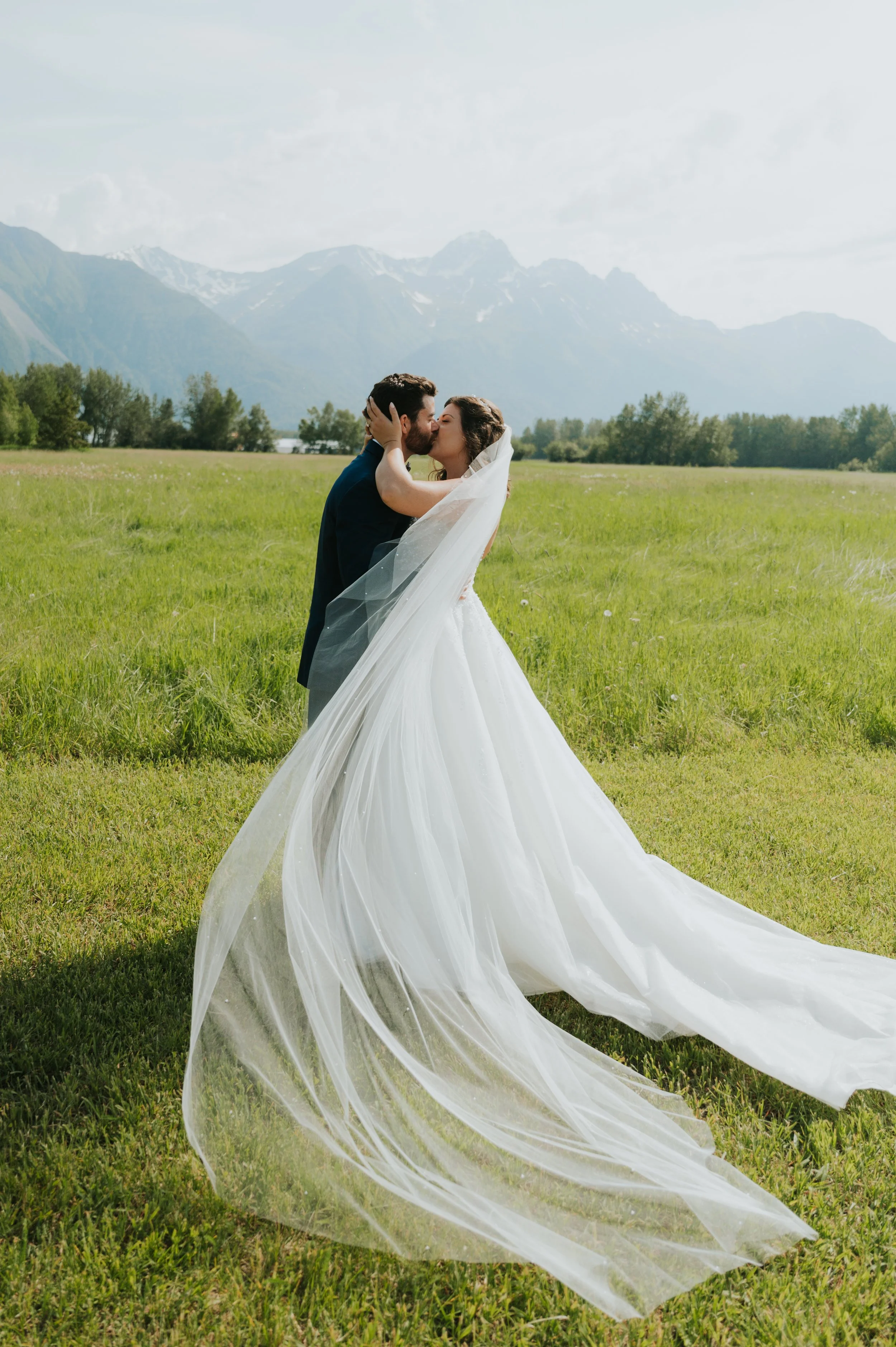bride and groom kissing in front of field