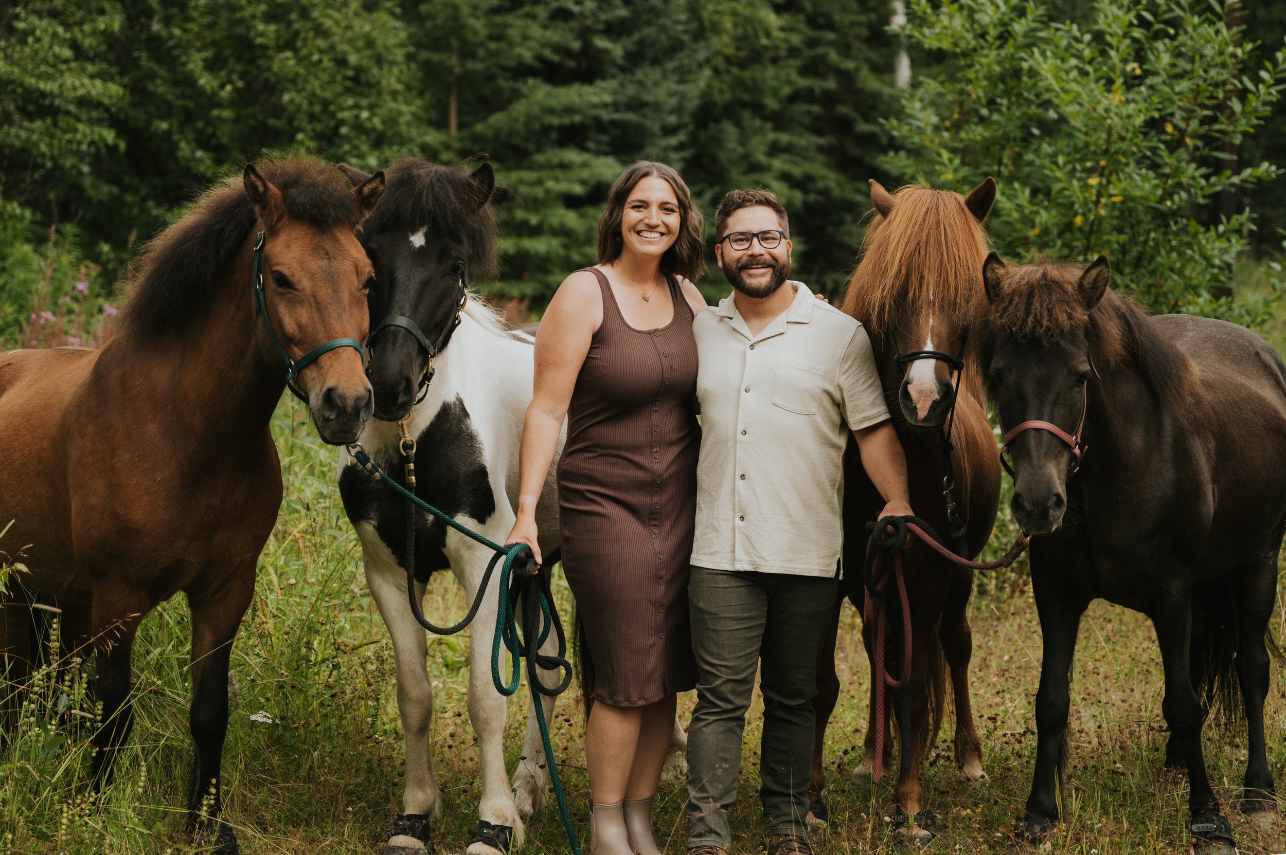 couple standing side by side holding four horses in halters