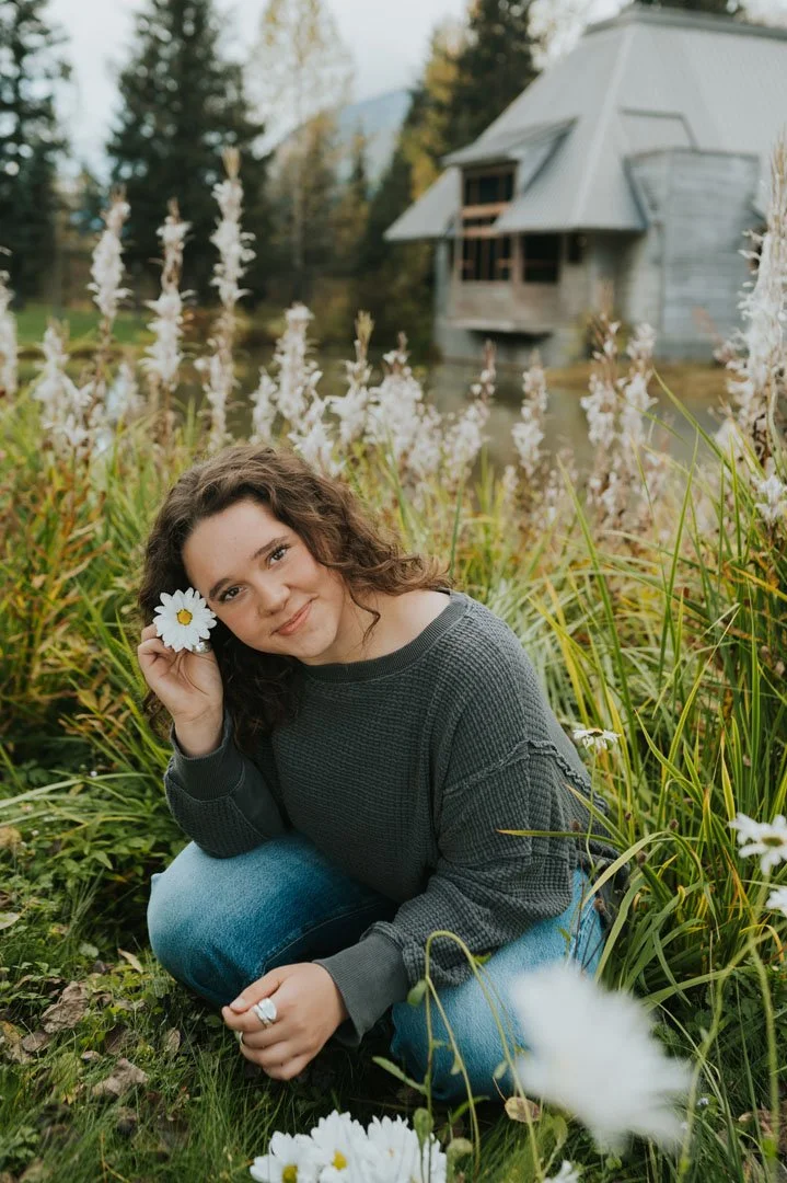 young woman in field putting flower behind ear