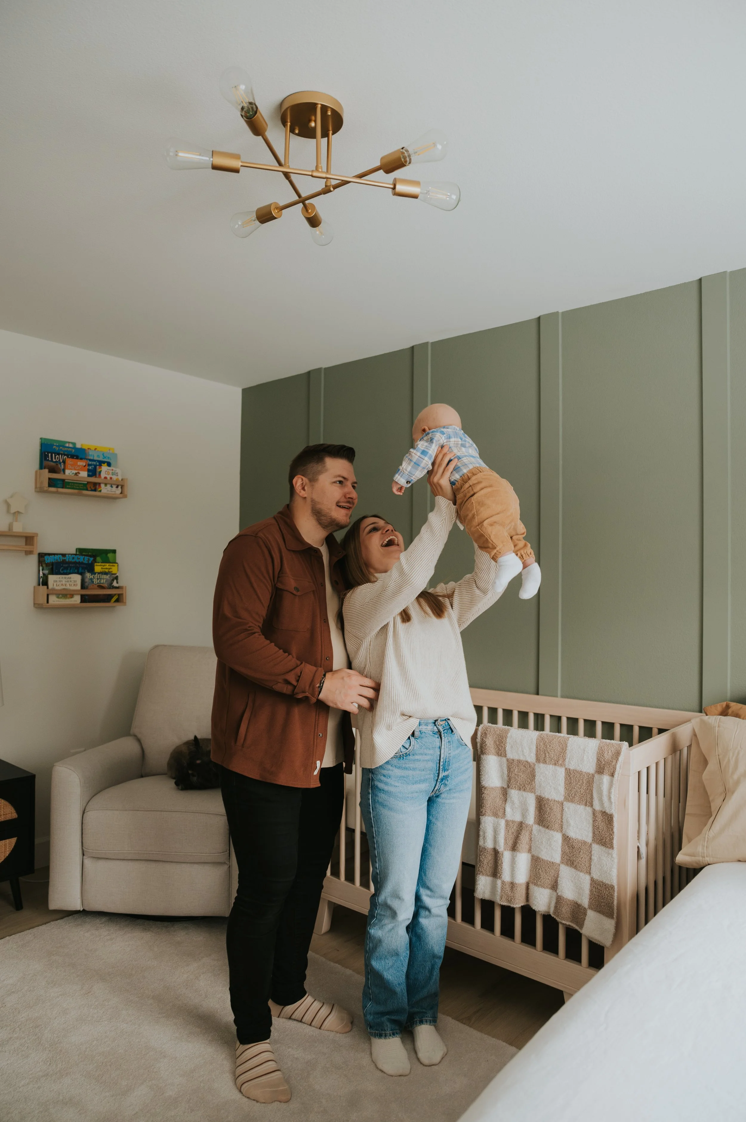two parents holding up infant in nursery