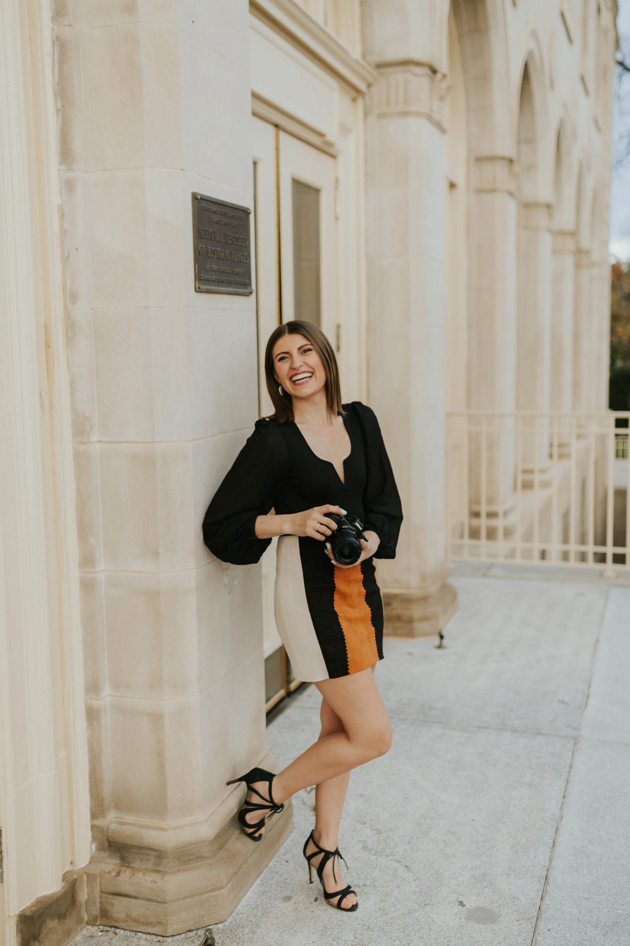 photo of mazzy holding camera leaning against old architecture