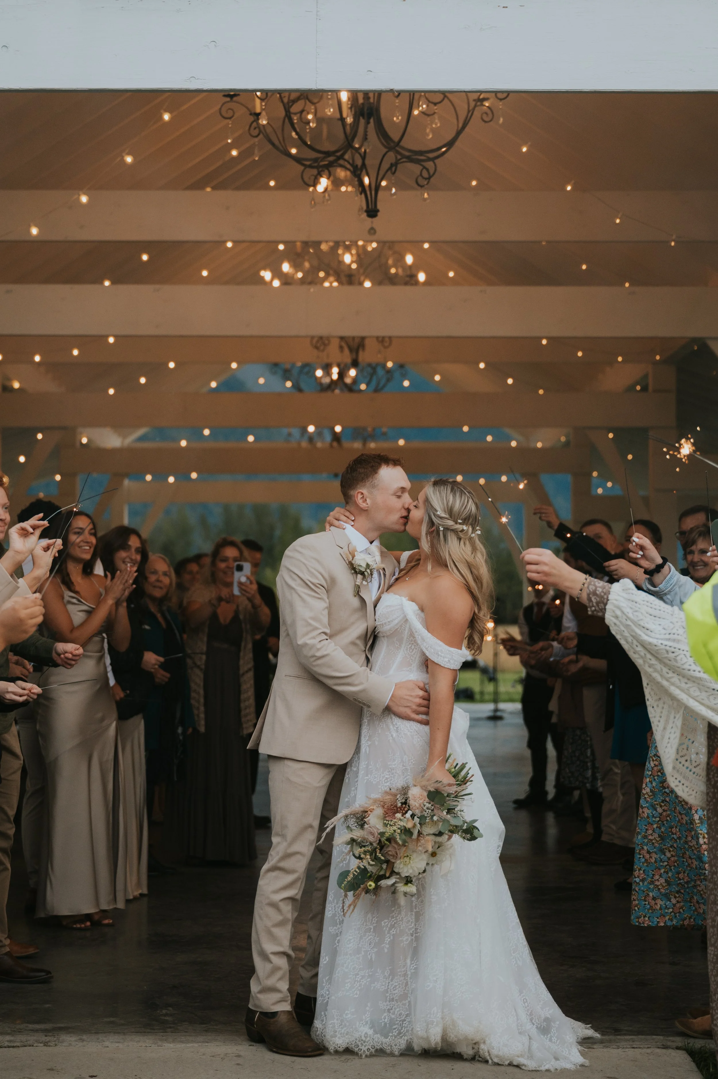 bride and groom kissing surrounded by guests and sparklers