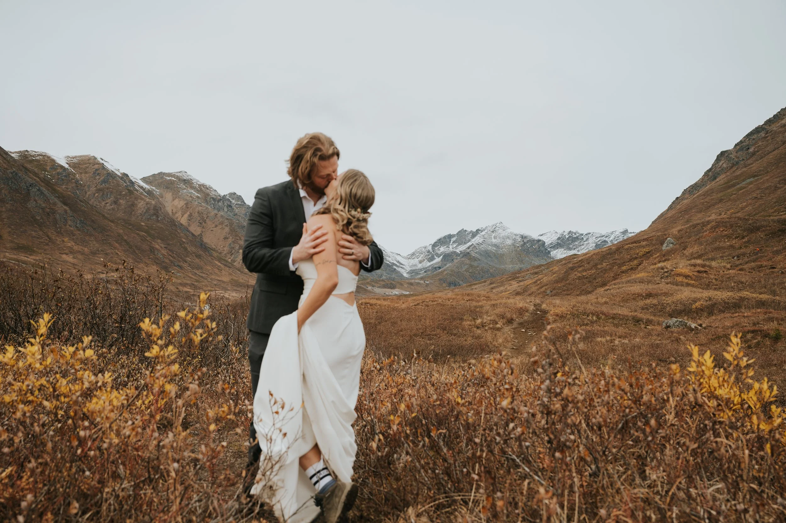 bride and groom kissing on mountainside
