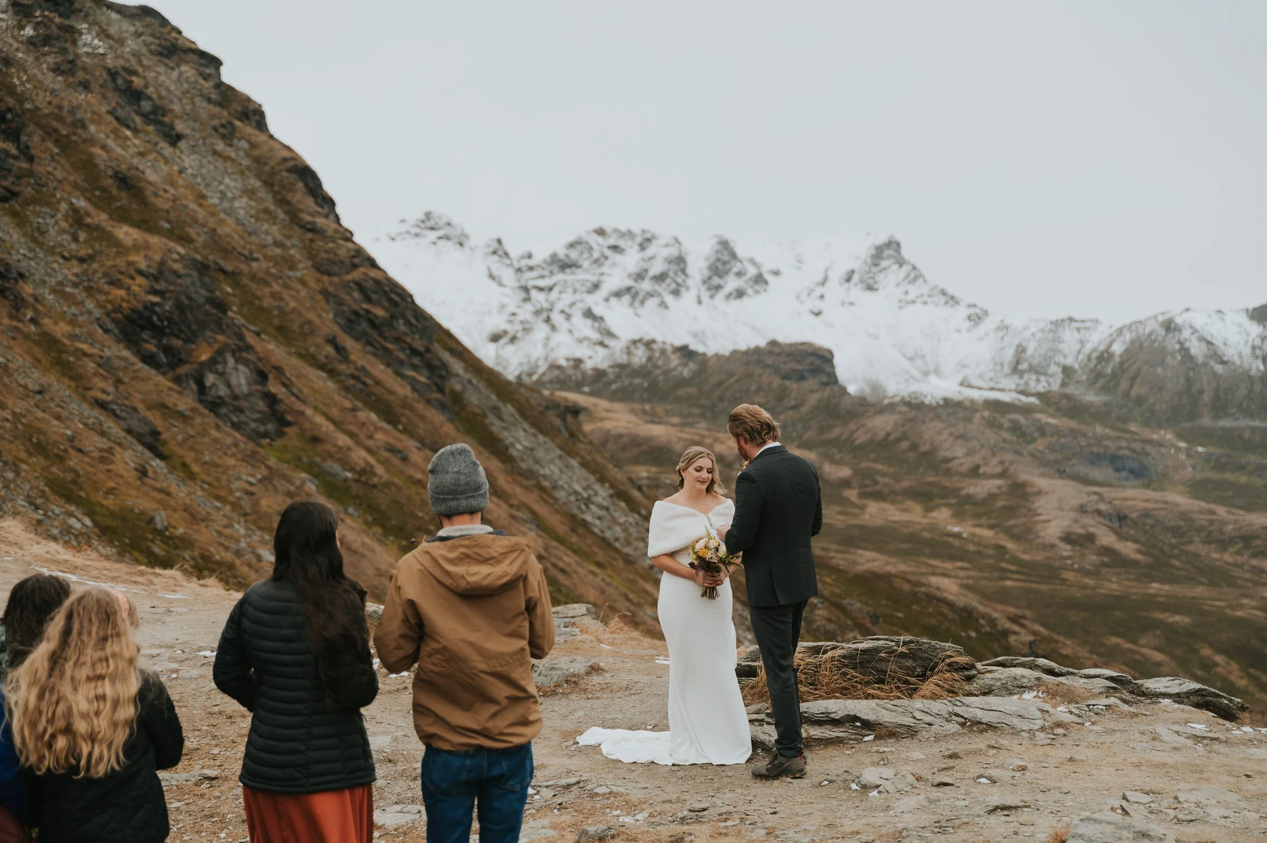 bride and groom exchanging vows with a few guests on mountainside