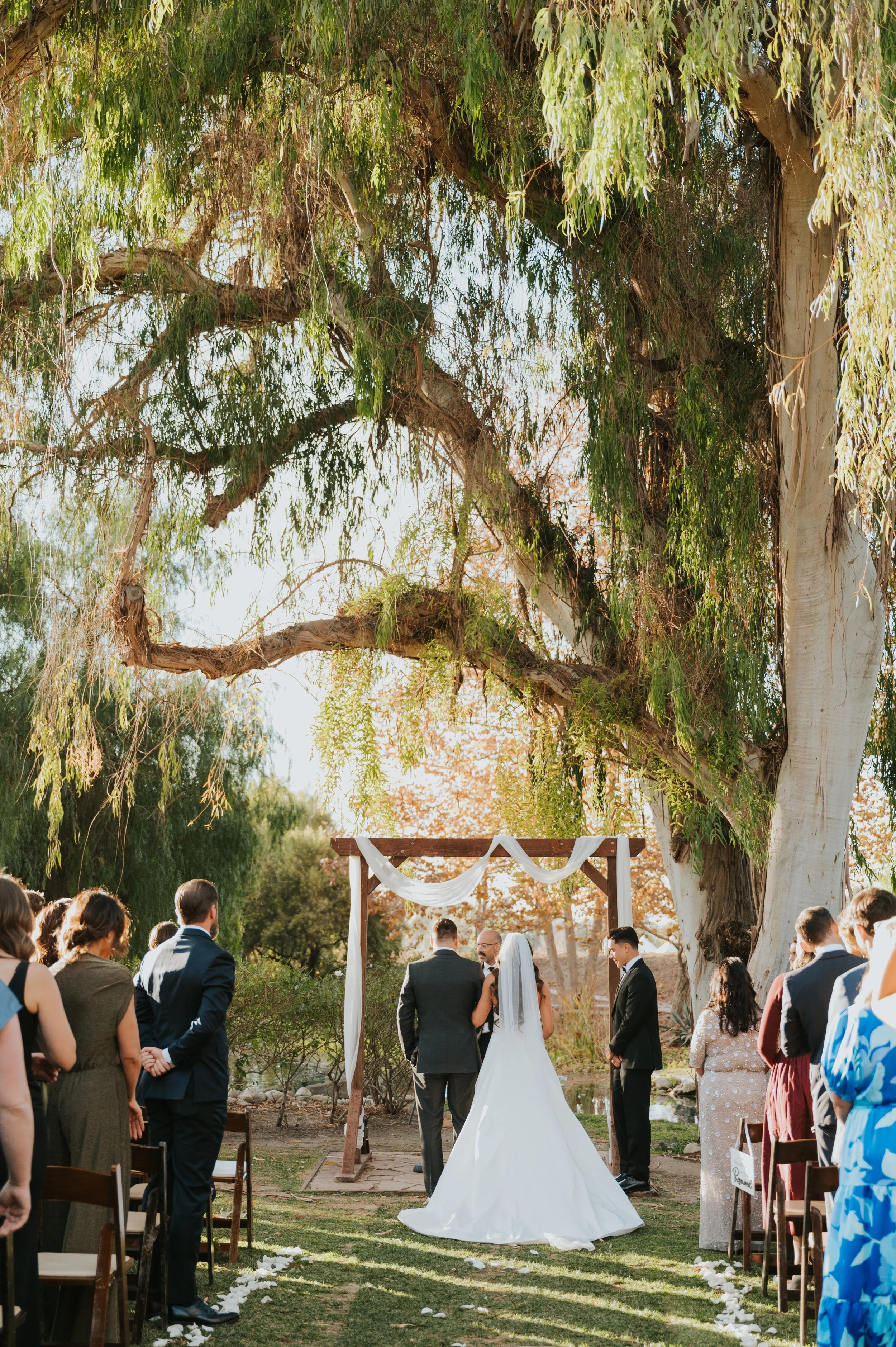bride at altar with father under large tree