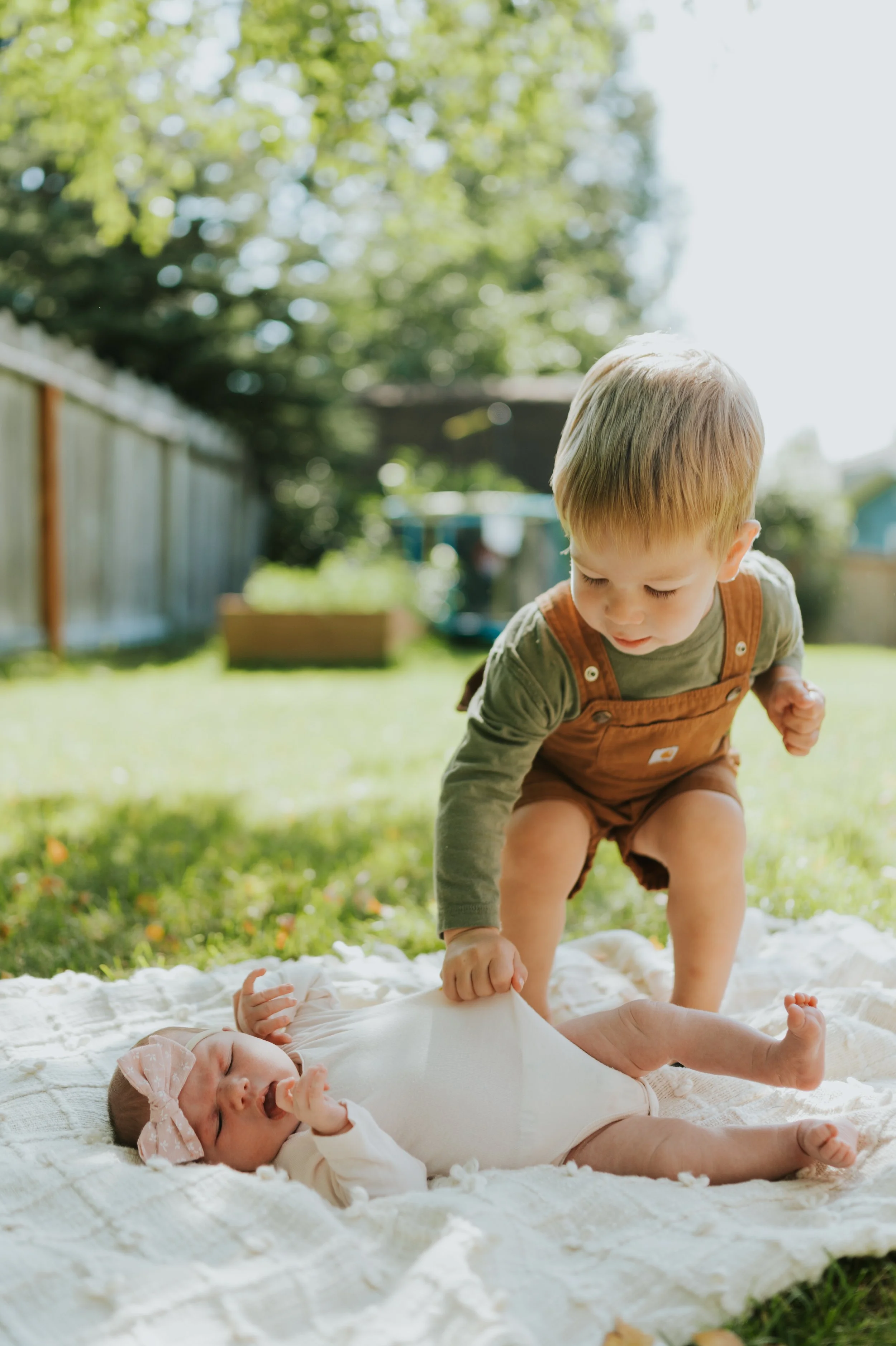 toddler touching infant outside