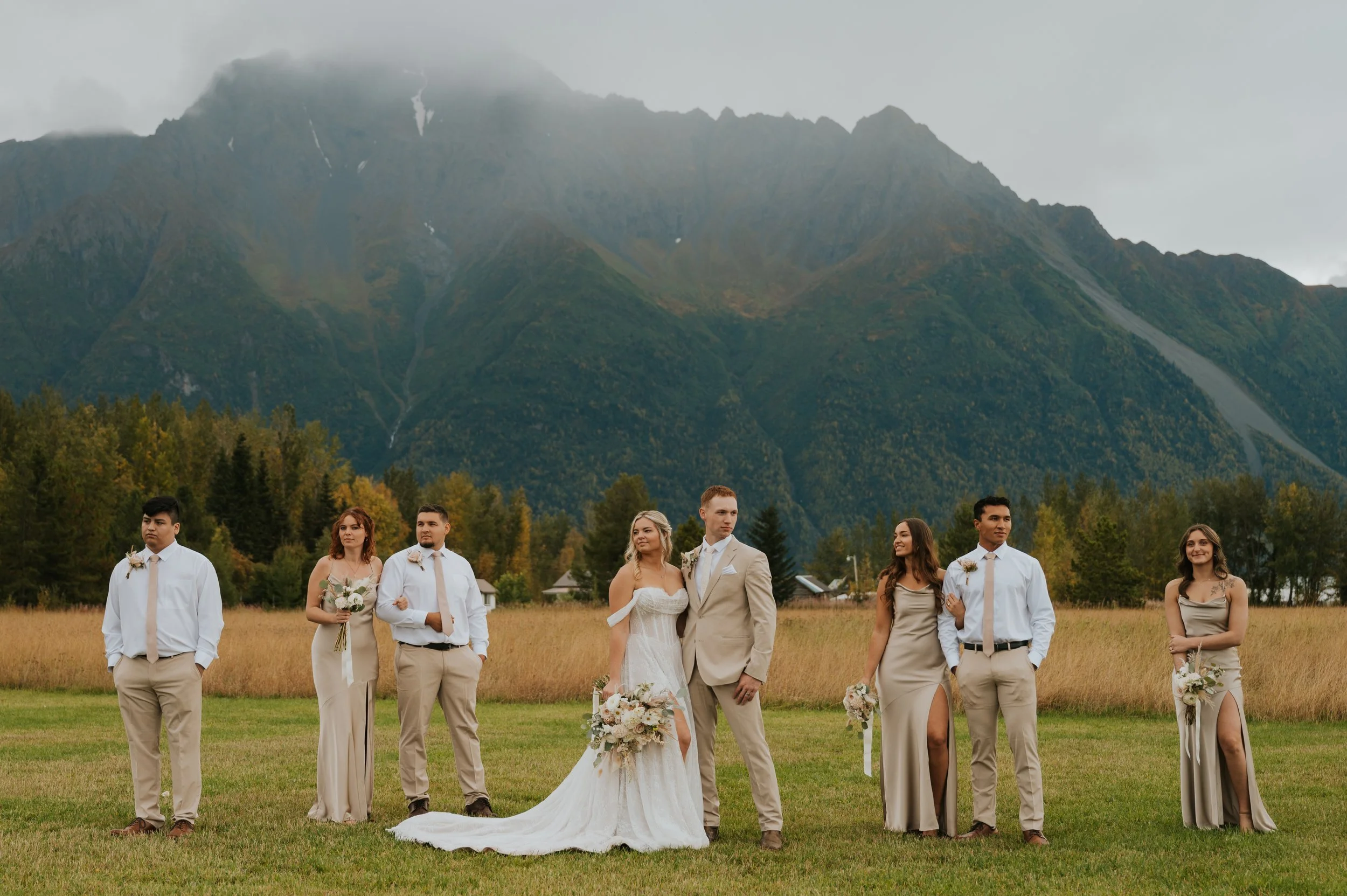 bride and groom in front of mountains with wedding party