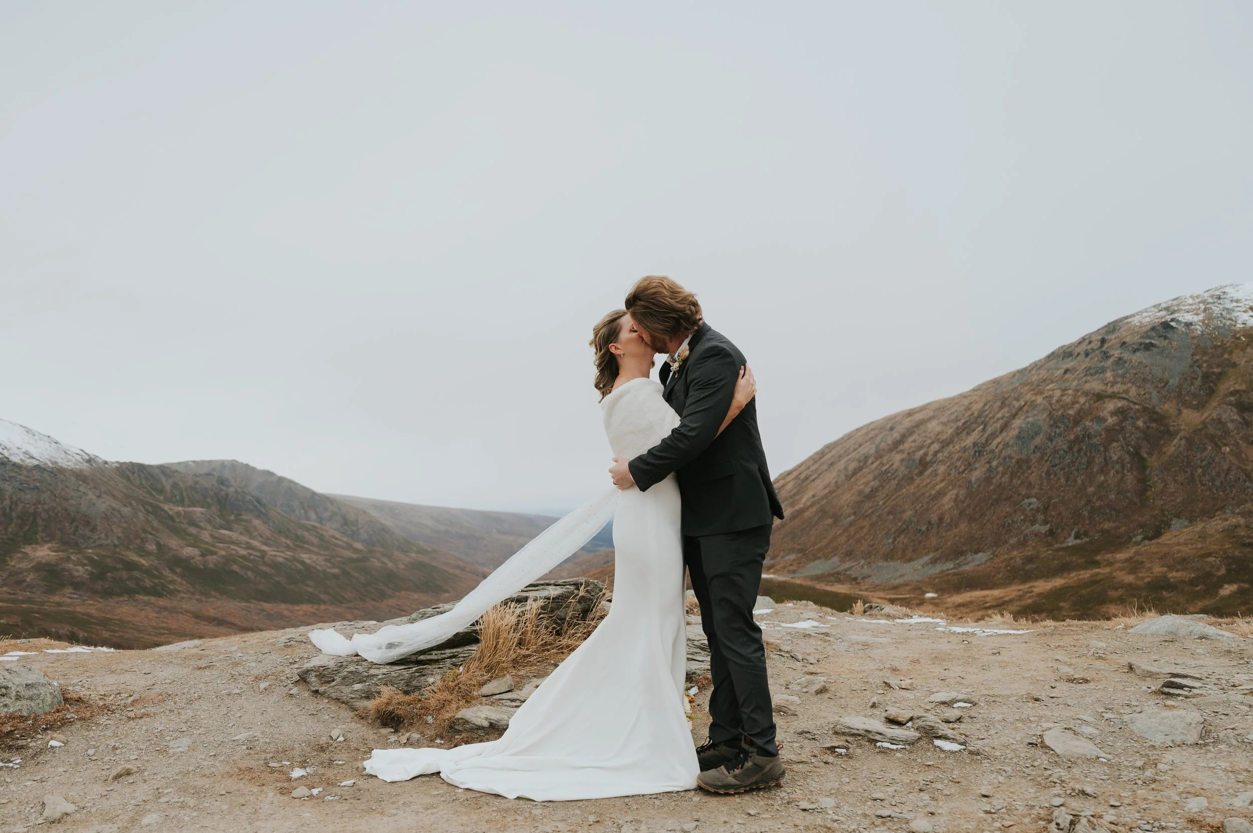 bride and groom kissing on mountainside