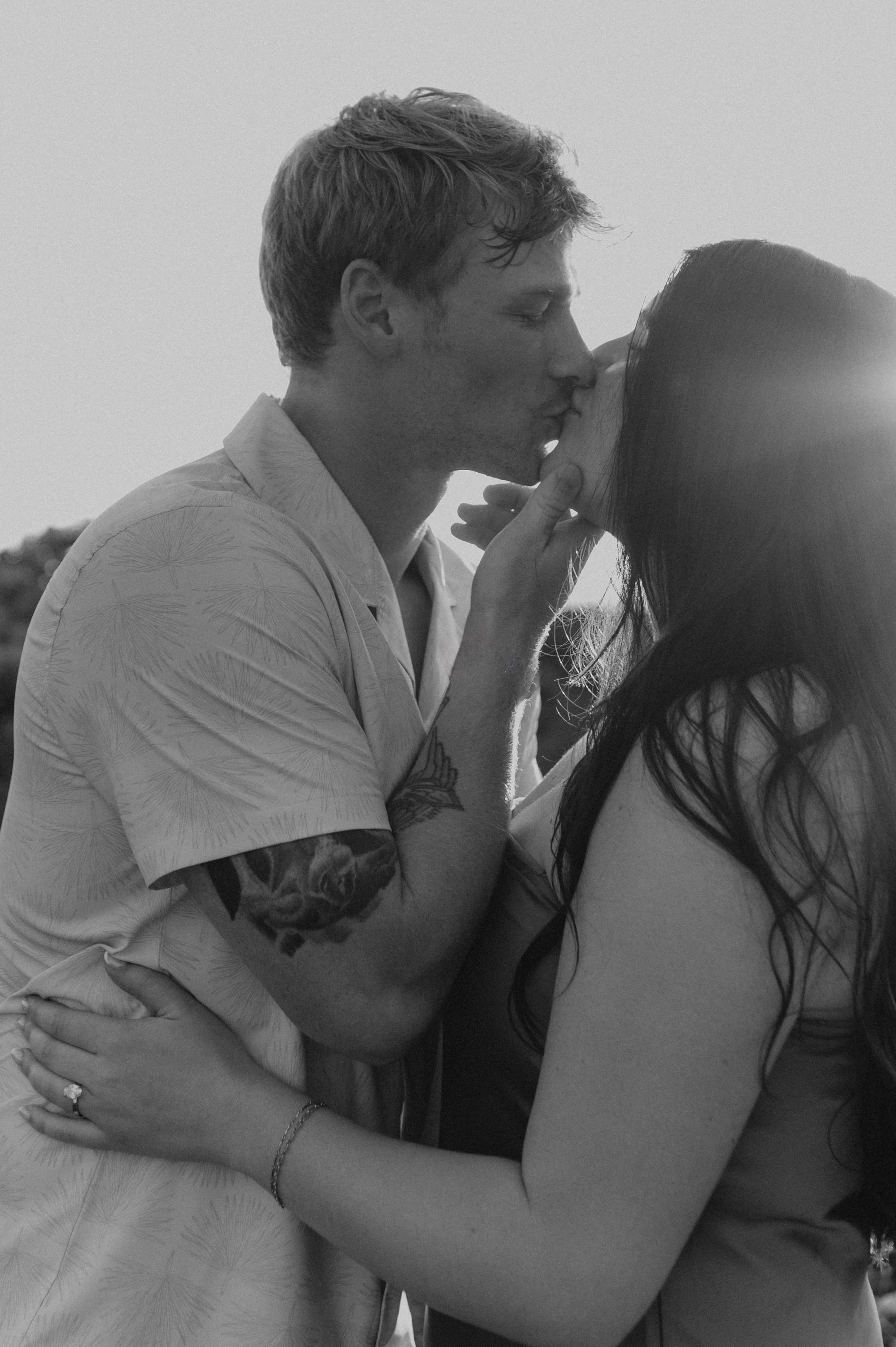 black and white closeup of couple kissing in with sun flare