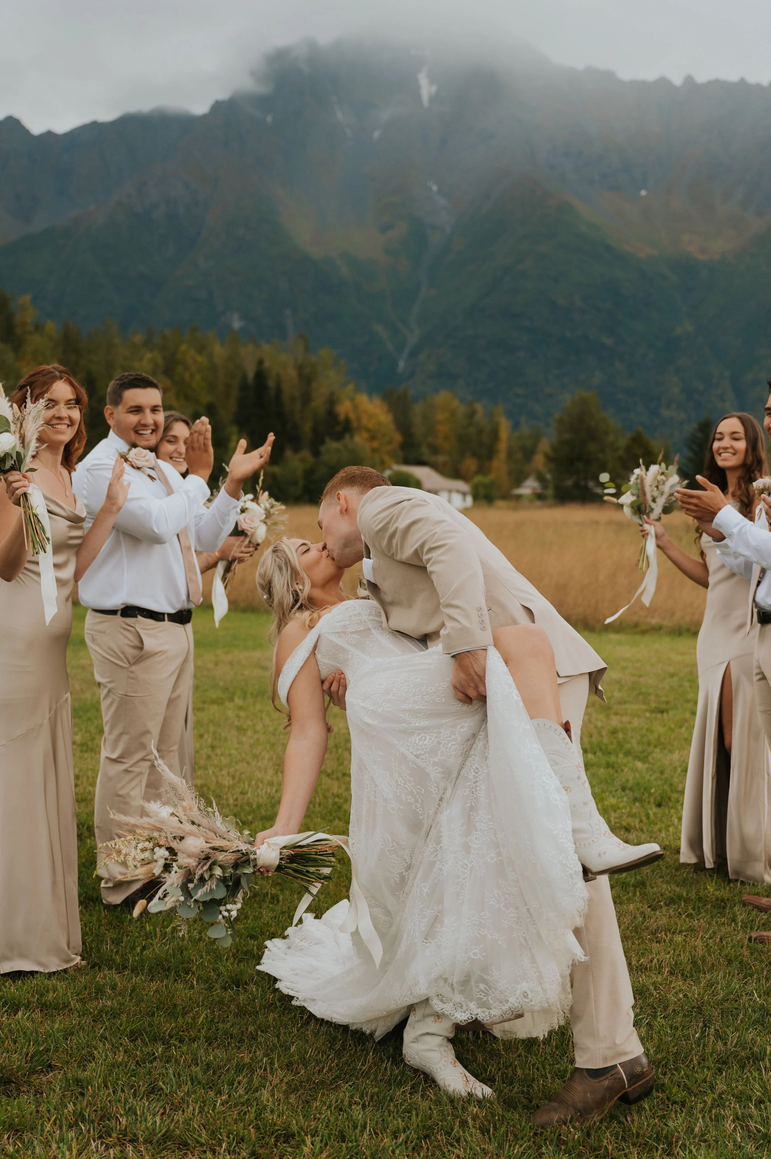 bride and groom dip kiss surrounded by wedding party