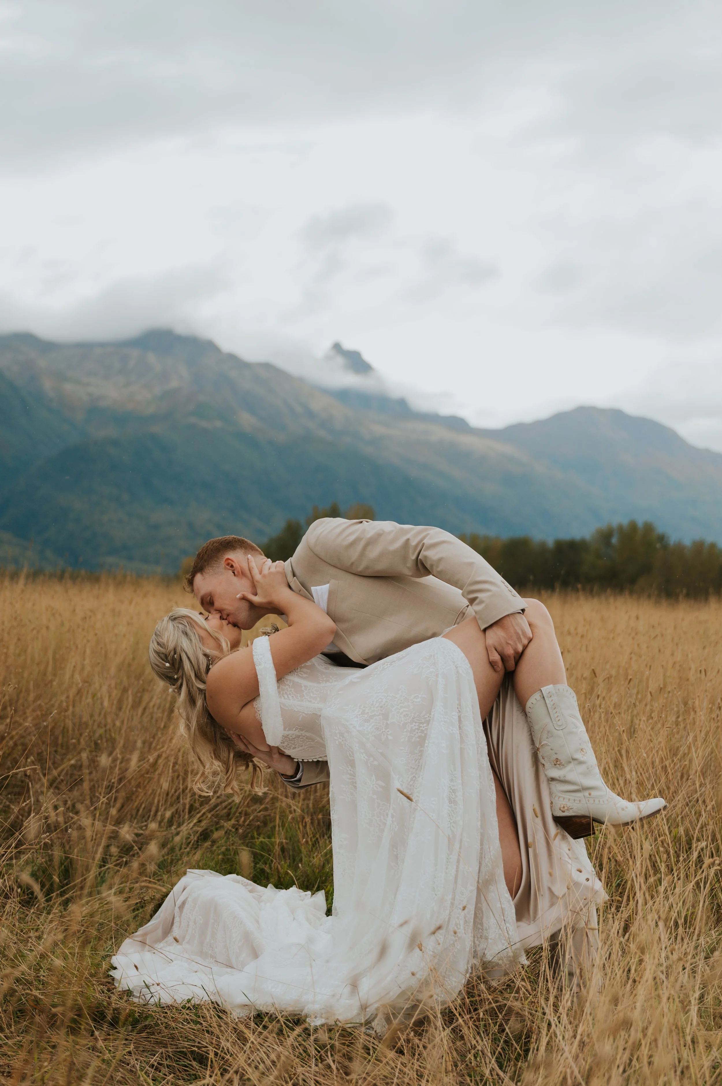 bride and groom in front of mountains kissing