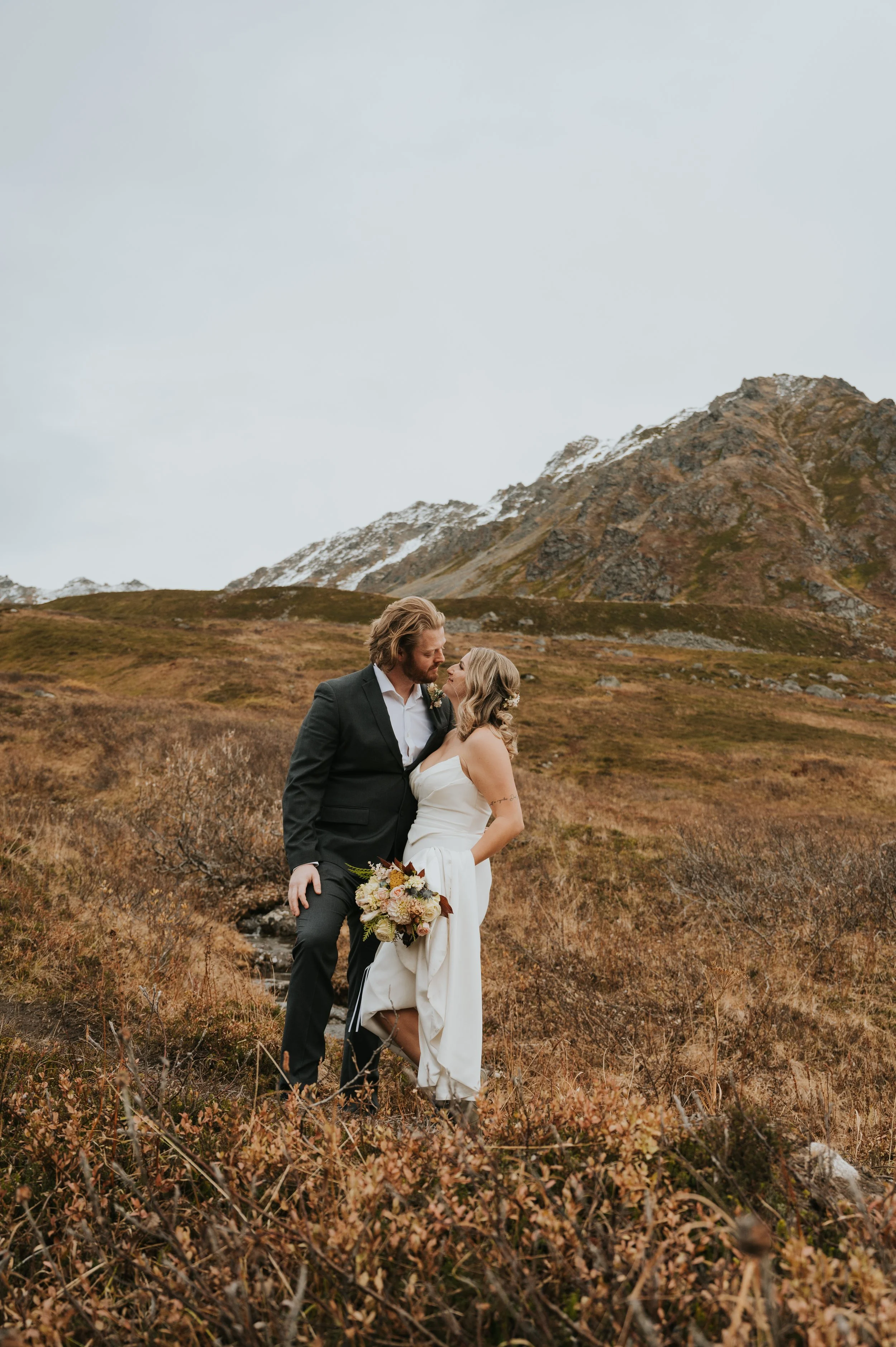 bride and groom smiling at each other on mountainside