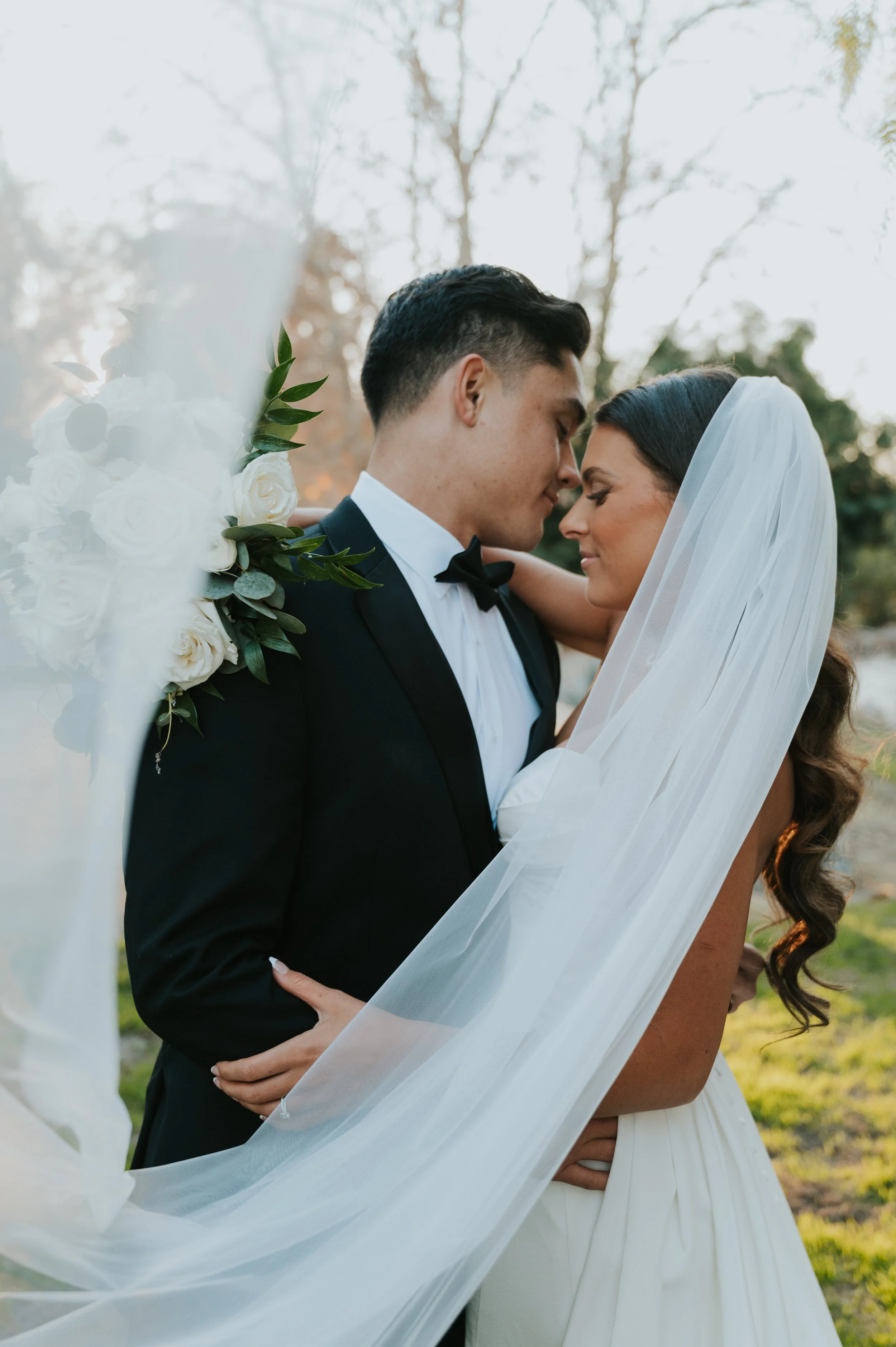bride and groom touching noses in wedding attire