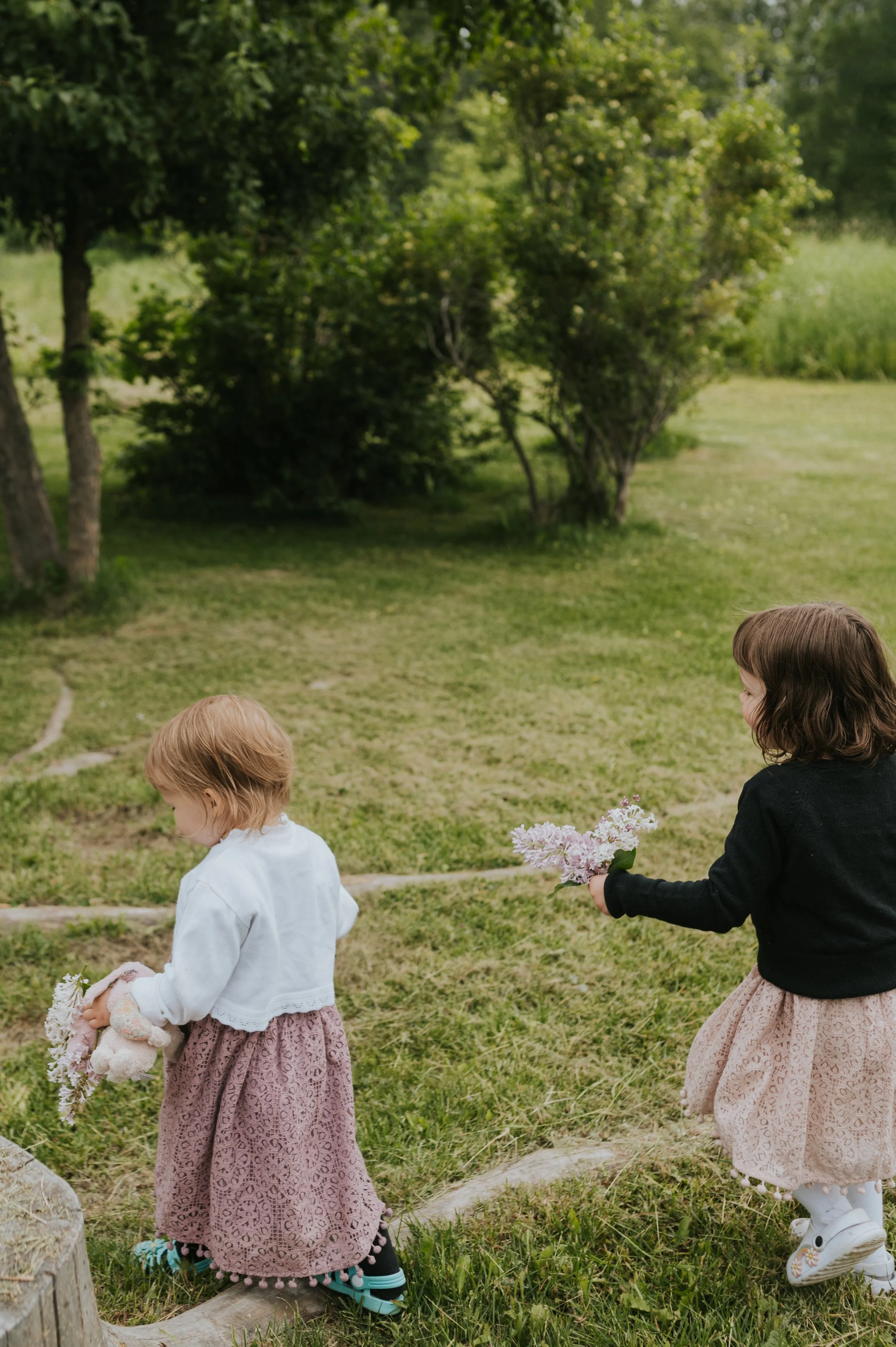 little girls holding hands and wandering around grass field