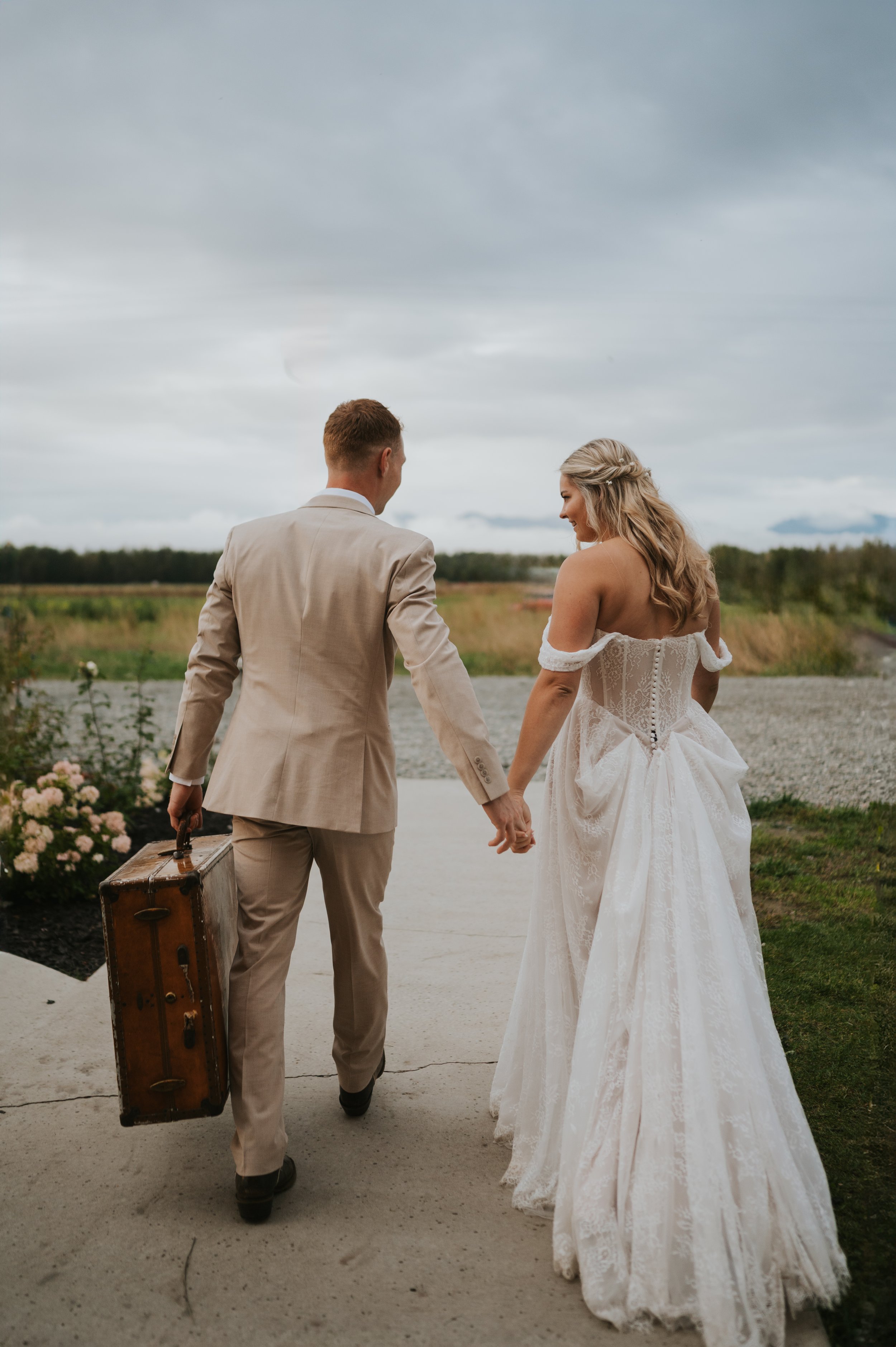 bride and groom walking away with vintage baggage