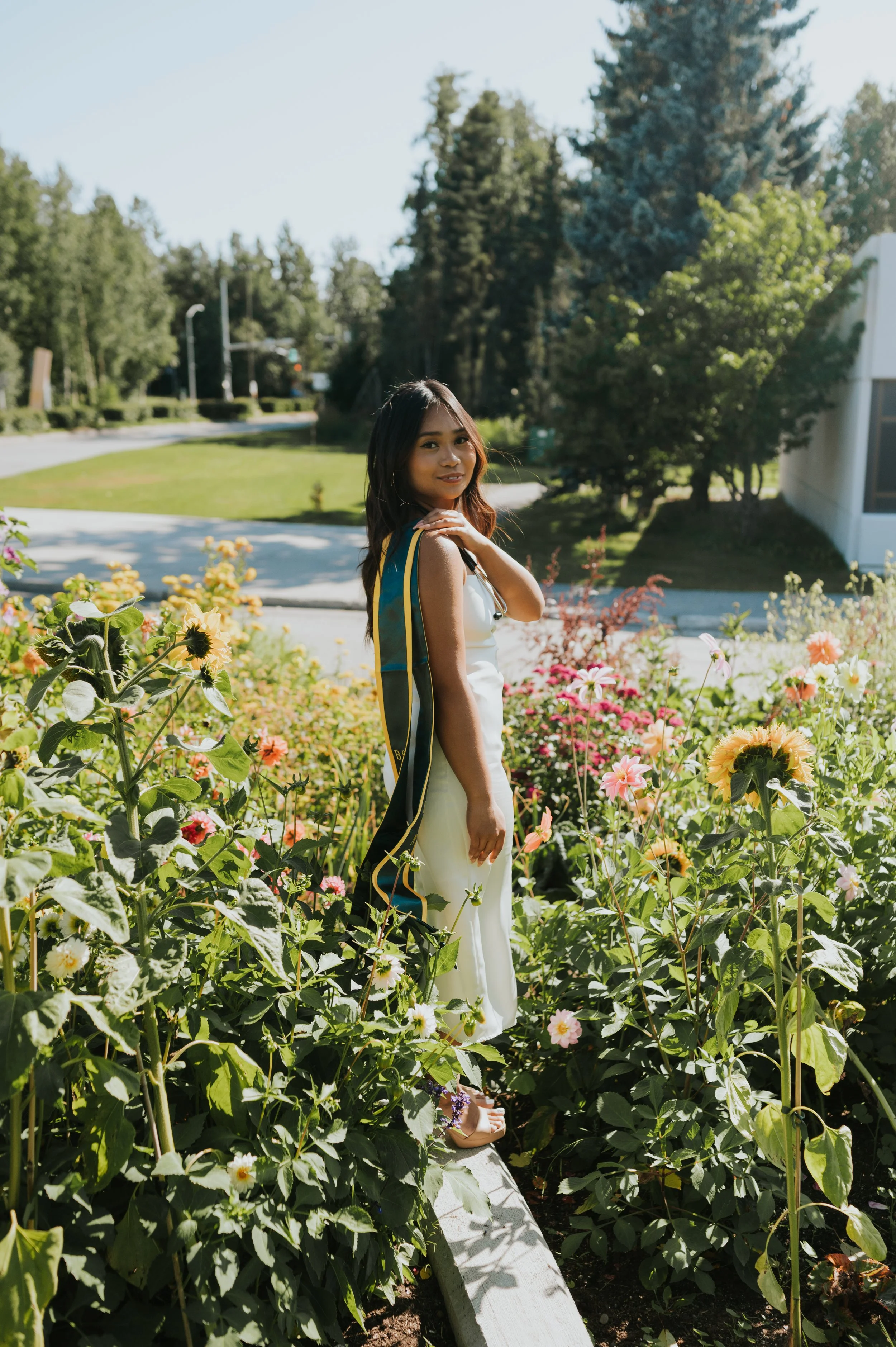 girl in graduation regalia smiling at camera in flowers