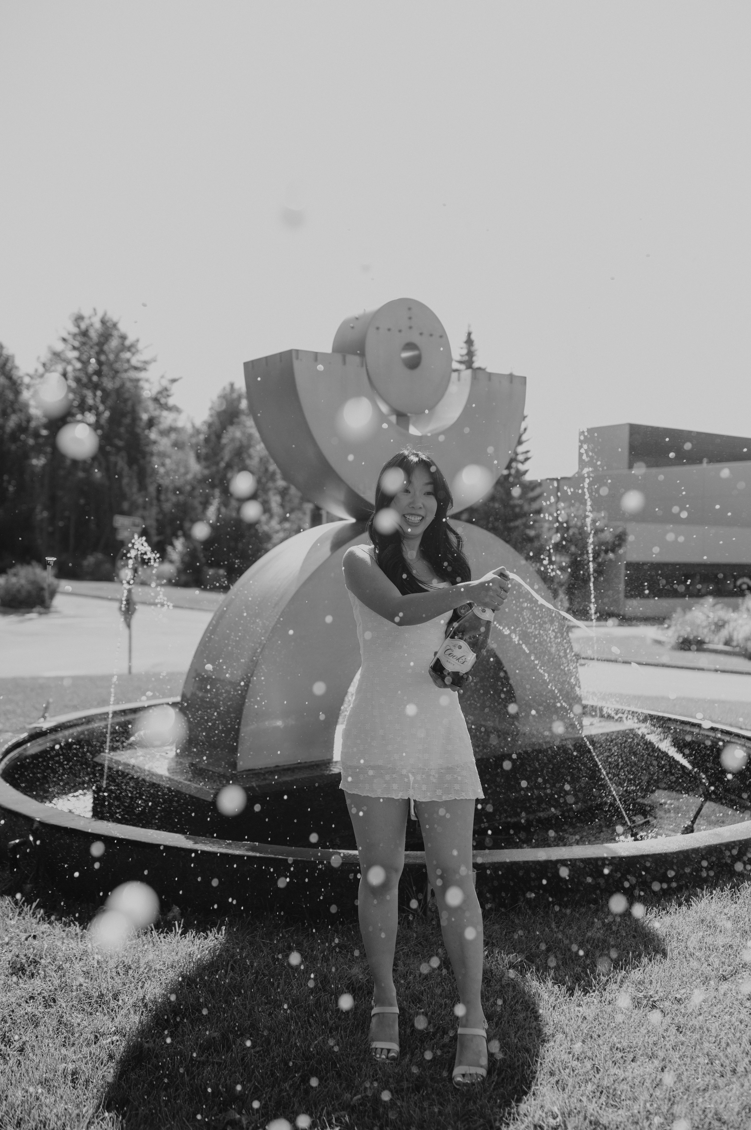 girl popping bubbly drink in front of fountain