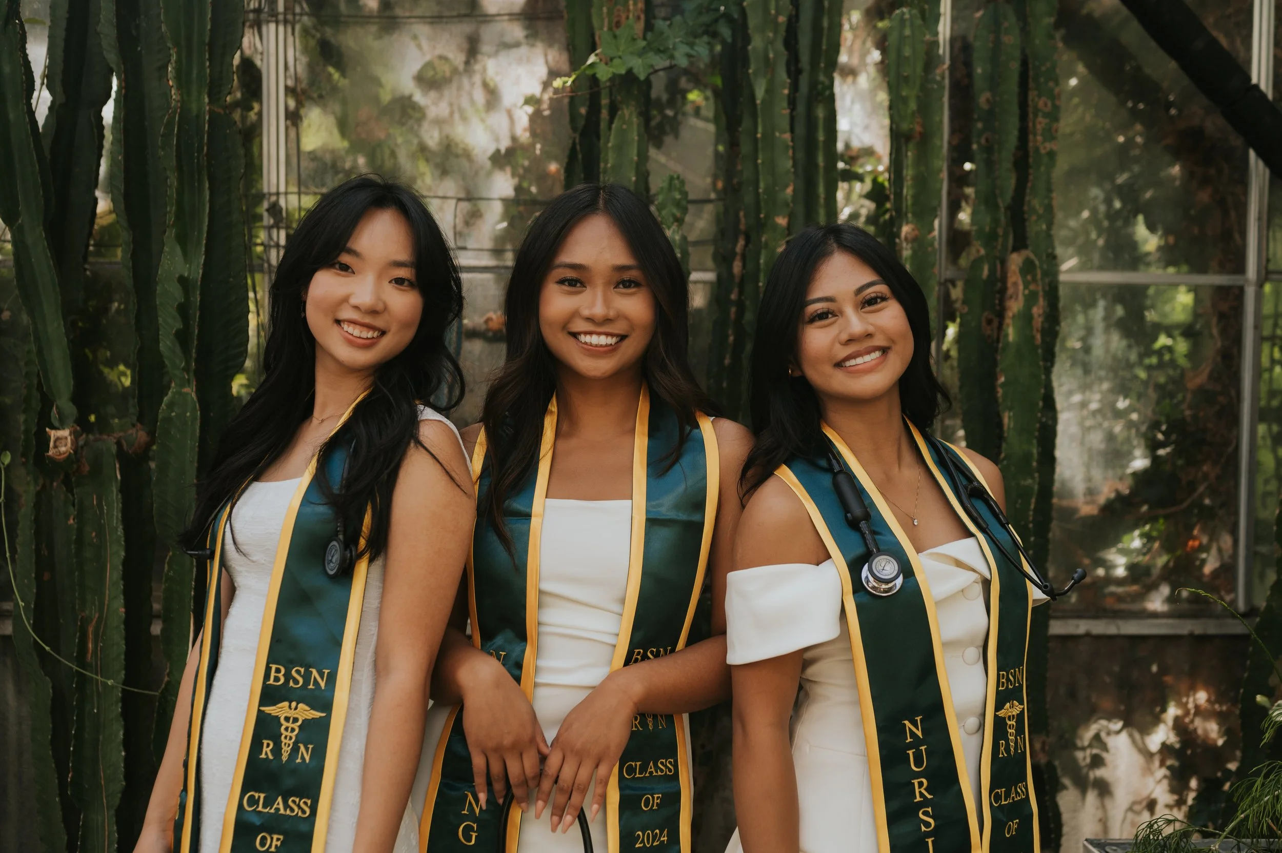 three girls with graduation regalia smiling at camera