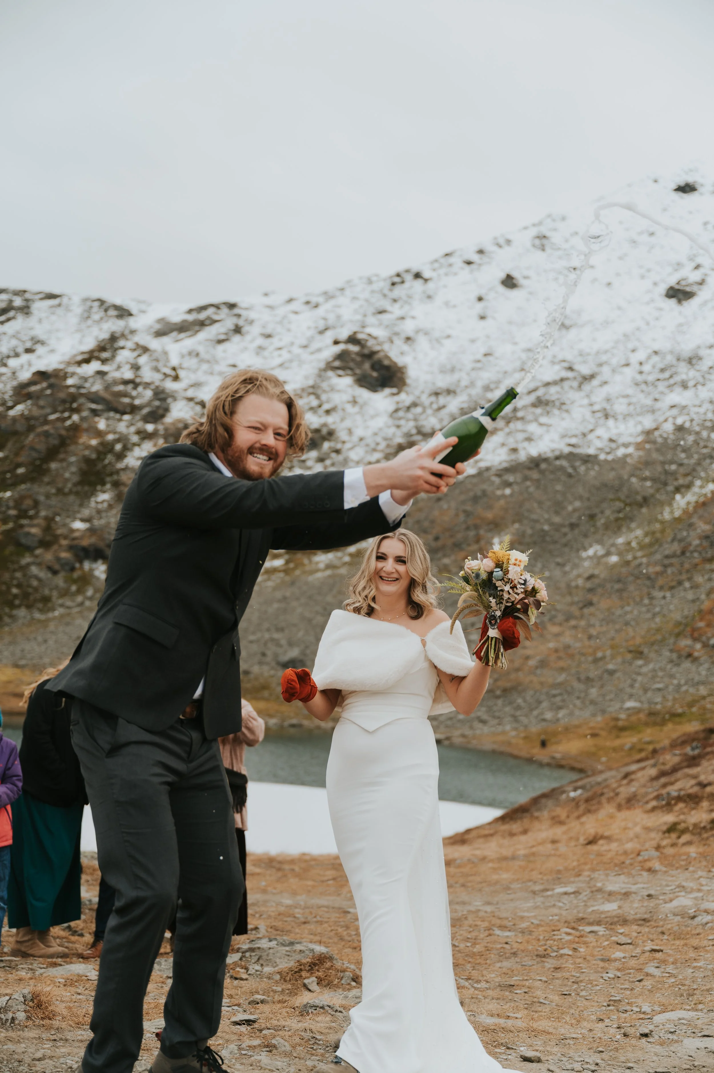 Image of couple popping bubbly beverage on mountainside