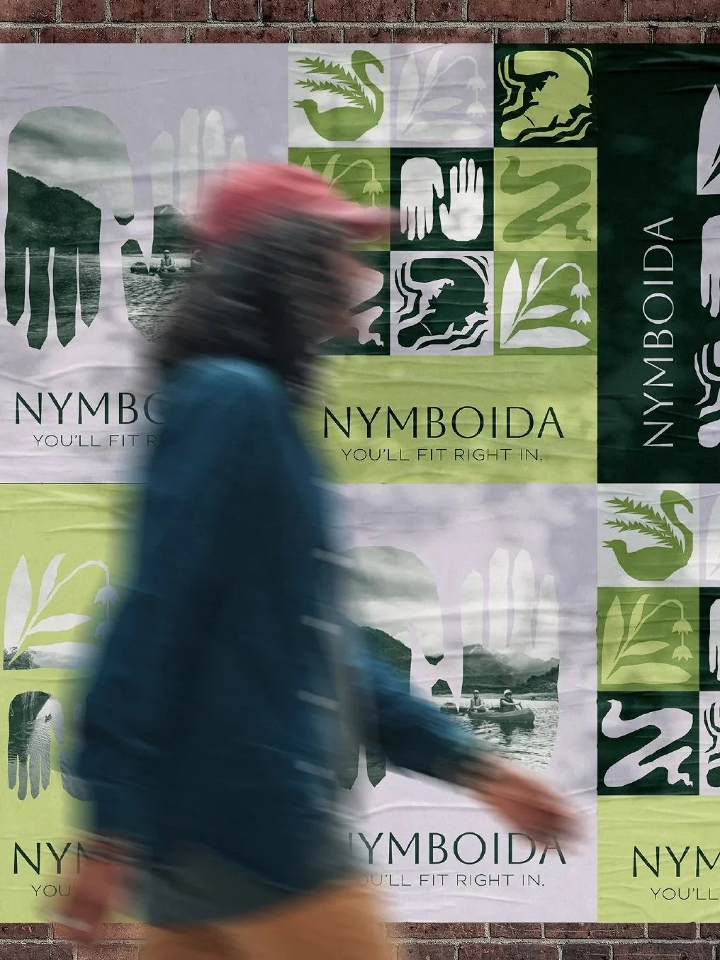 A person wearing a red cap and blue jacket walking past a wall with a Nymoida advertisement poster featuring eco-friendly symbols and nature images.