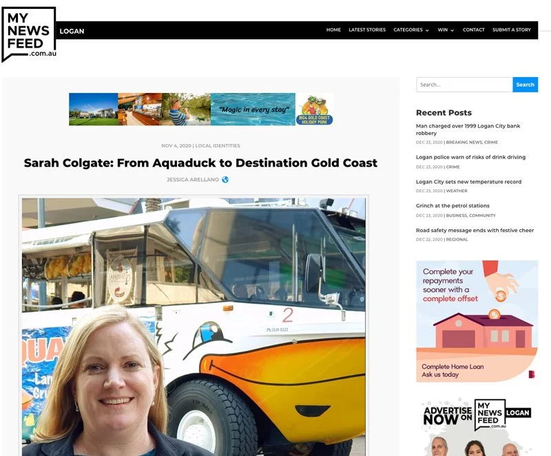 A woman with blonde hair smiling in front of a colorful boat or watercraft, with a clear sky background.