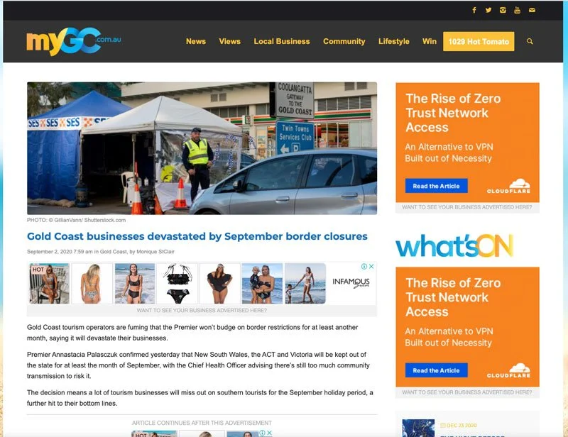 Photo showing a roadside COVID-19 testing or checkpoint station with a tent, a person in a yellow vest, traffic cones, and cars in the background.