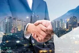 Two people shaking hands over a cityscape background with skyscrapers and mountains.