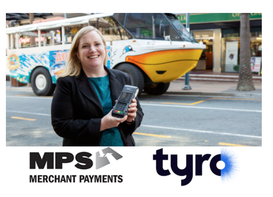 A woman smiling and holding a payment terminal stands on a city street with a colorful tour bus and palm trees in the background.