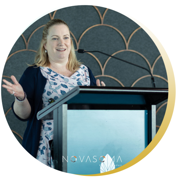 A woman speaking at a podium with a microphone, gesturing with her hands during a presentation or speech.