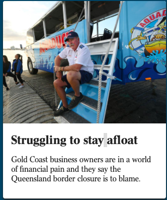 Man sitting on steps next to a colorful boat with 'AquaDuck' logo, at a dock, with people walking in the background.
