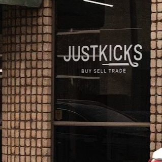 Storefront window with the sign 'JUSTKICKS' and the words 'BUY SELL TRADE' underneath.