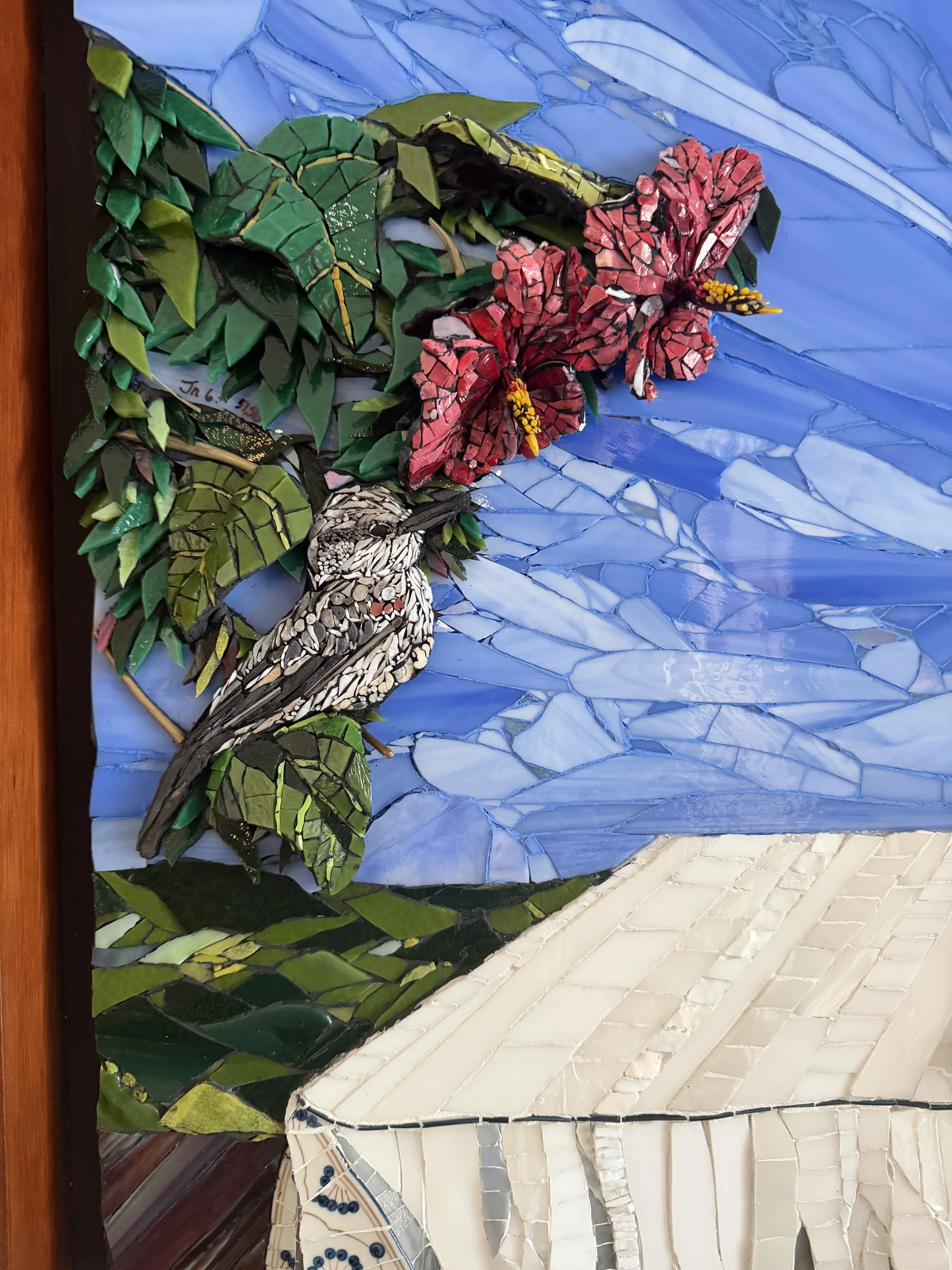 Array of broken tiles, colorful mosaic pieces, and rocks with tools like pliers on a work surface.