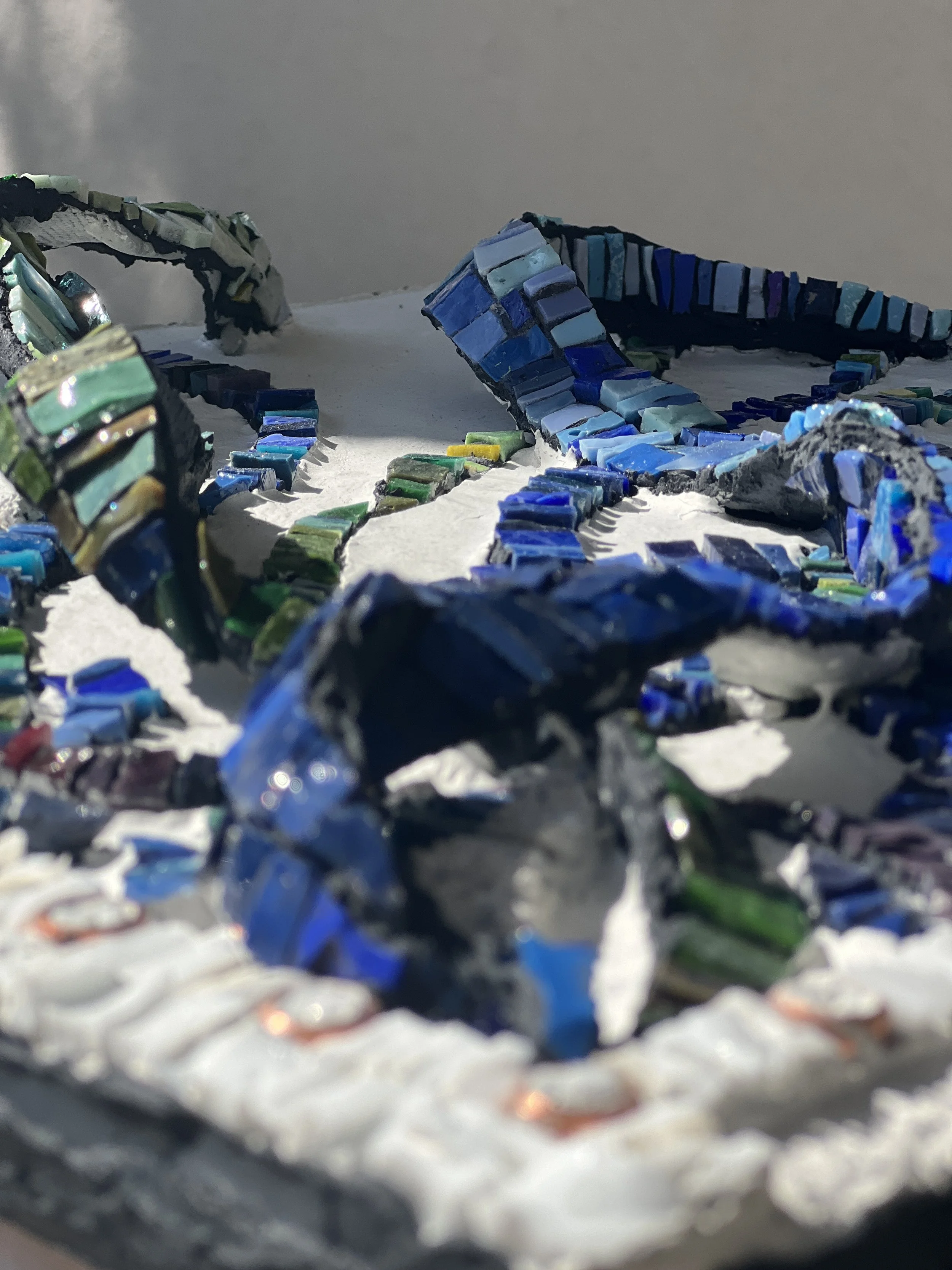 Mosaic art of a woodpecker bird with a red crest, black and white body, mounted on a wooden wall.