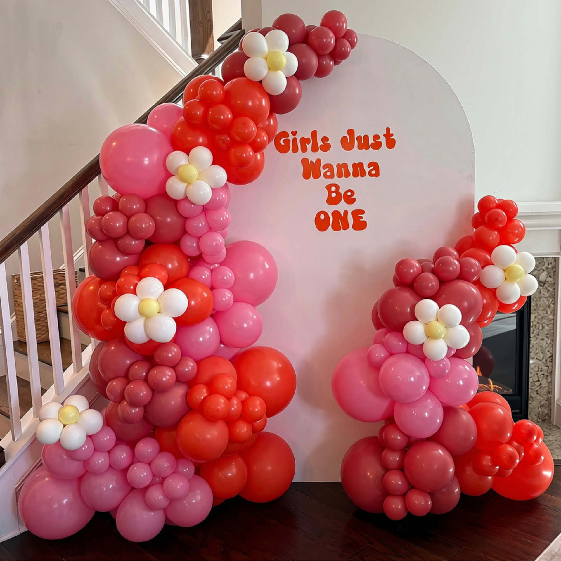 Pink and Orange Balloon Garland with White Daisy Flower Balloons around a White Arch Backdrop with the phrase "Girls Just Wanna Be ONE" in Orange font. The perfect backdrop for a 1st Birthday Party in Charleston/ Mount Pleasant, SC