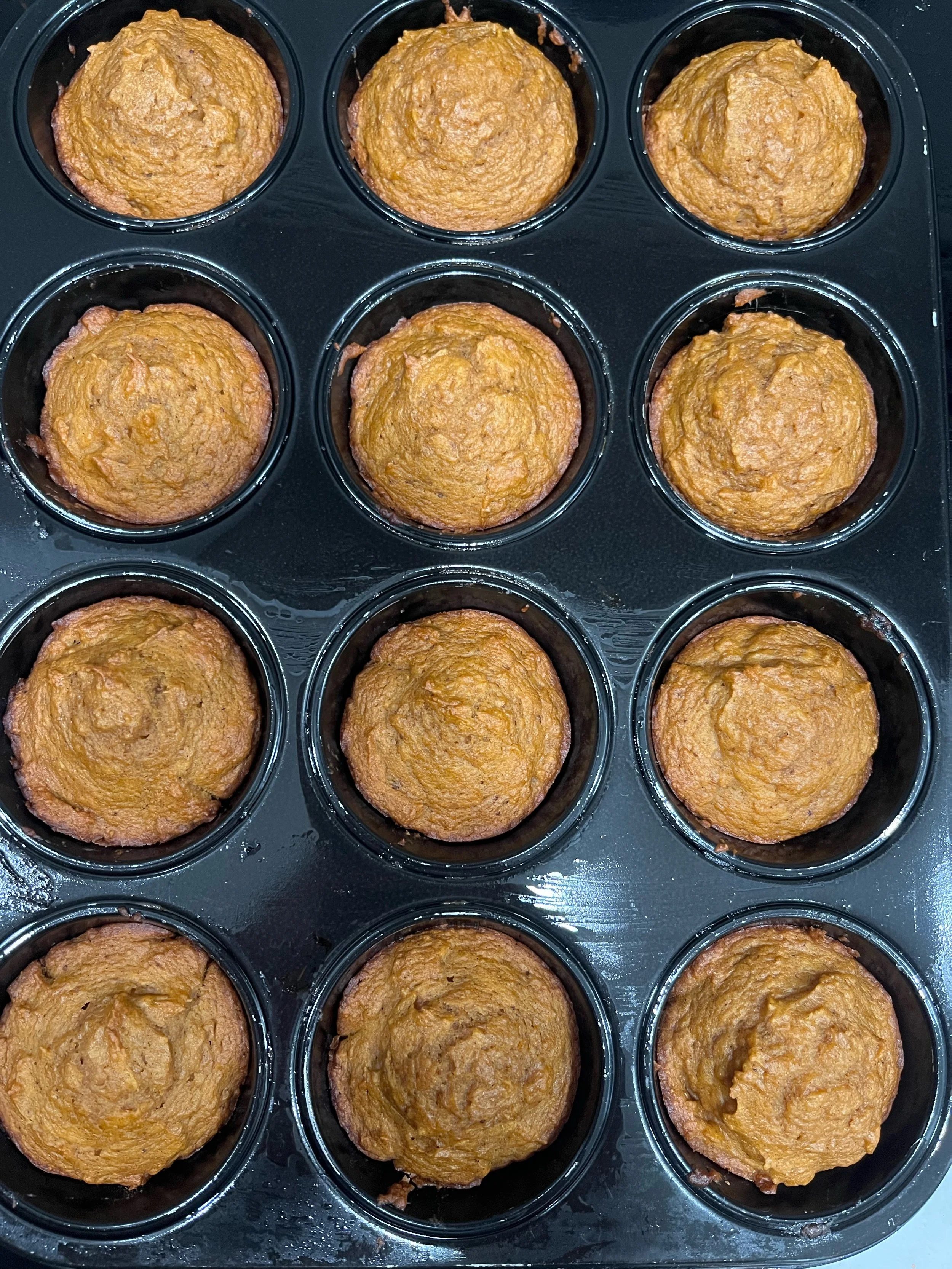 A muffin tin with twelve freshly baked vegan pumpkin muffins.