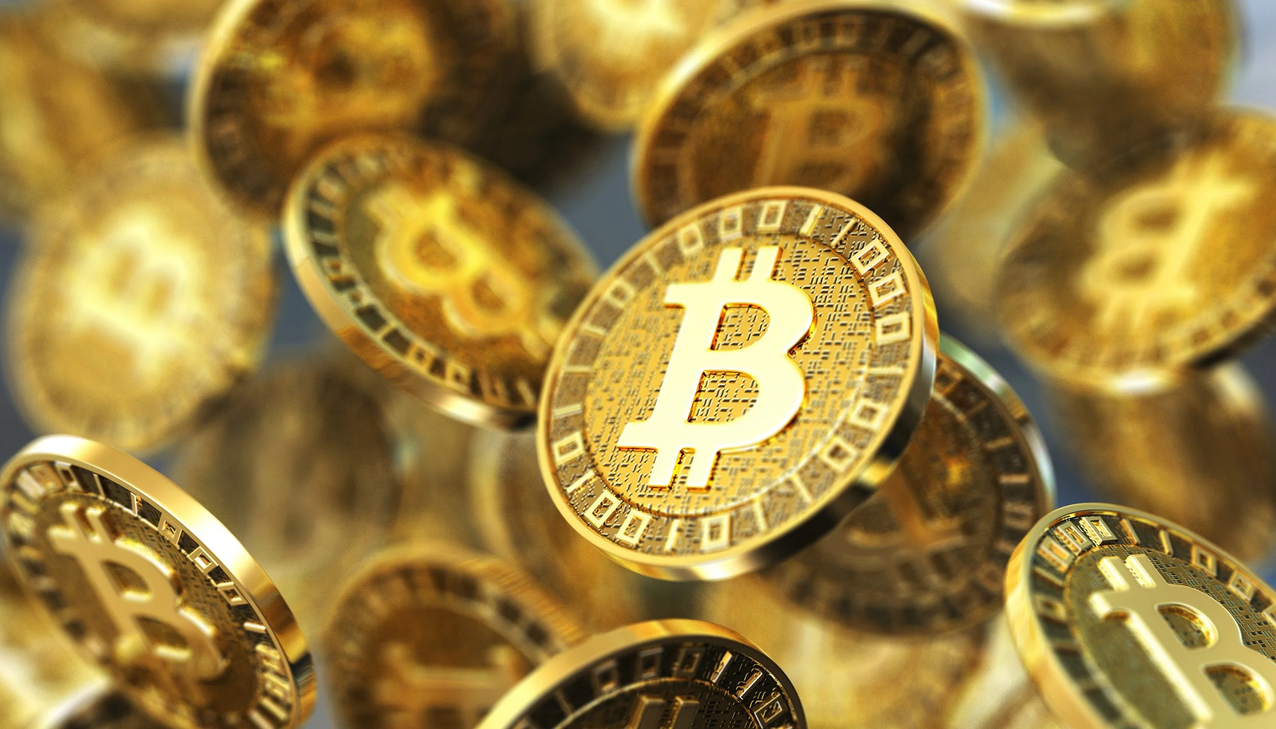Multiple gold-colored Bitcoin coins with digital circuit designs, with one coin prominently displaying the Bitcoin symbol.