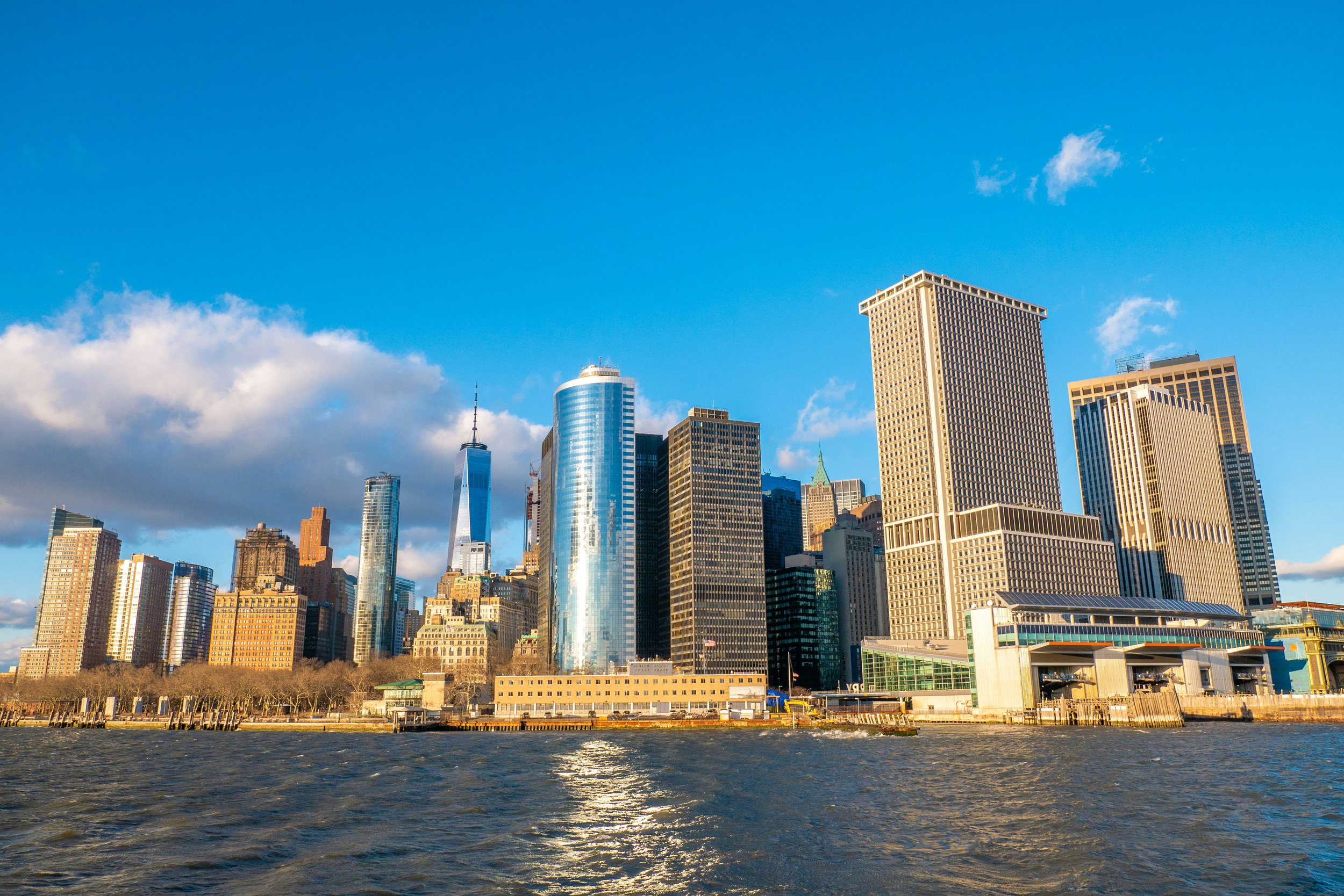 City skyline with modern skyscrapers viewed from the water under a blue sky with some clouds.