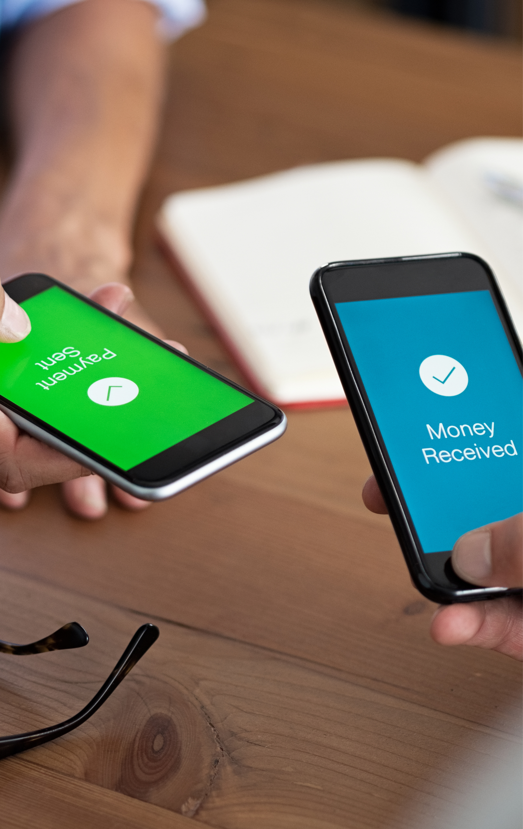 Two smartphones demonstrating a contactless money transfer, with one showing 'Payment sent' and the other showing 'Money received' on their screens.